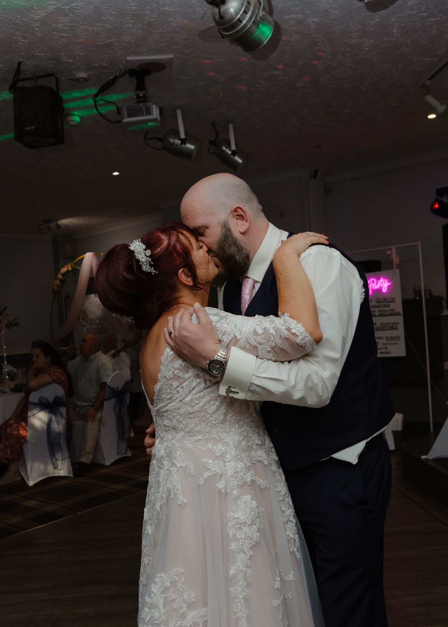 Couple sharing romantic dance moves under dim lighting at wedding reception.