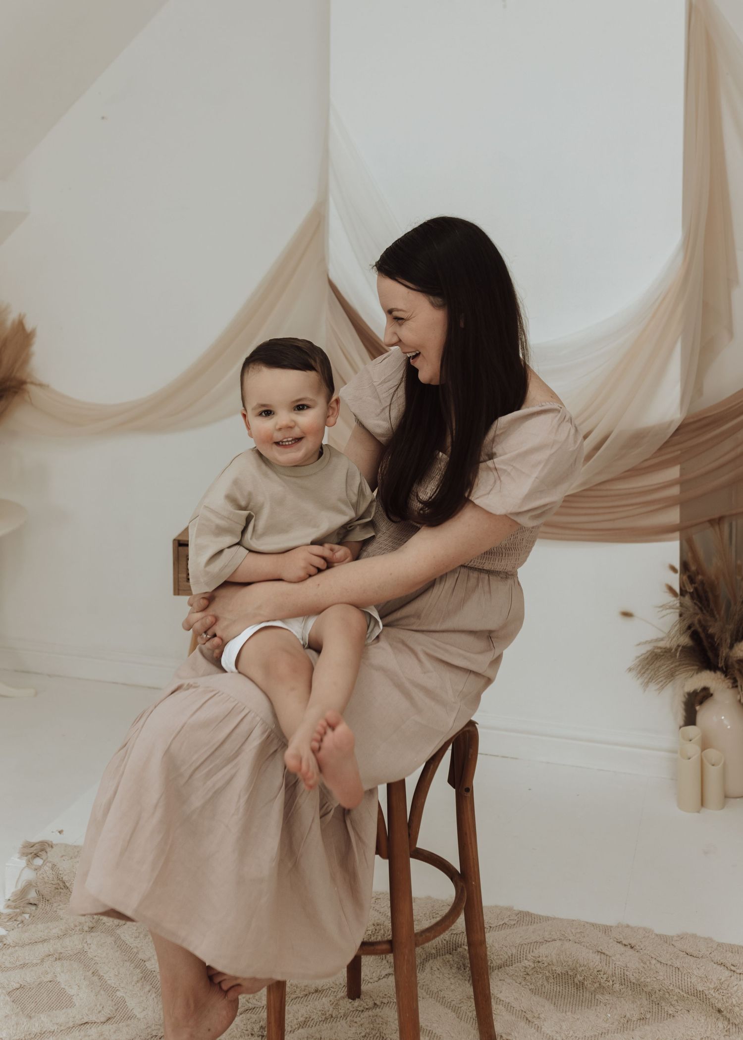 Candid family photoshoot with soft beige tones and natural interactions.