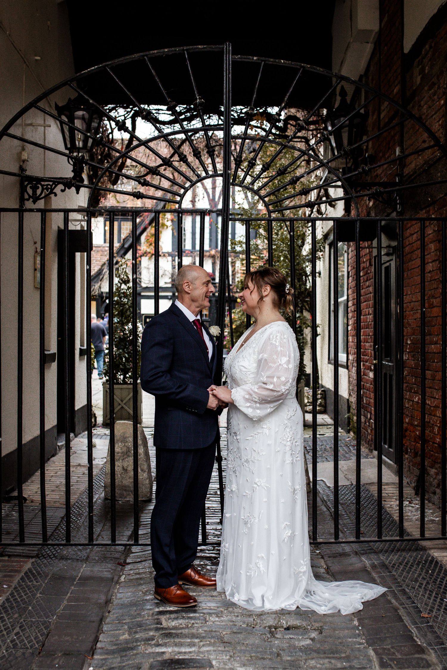 Couple sharing intimate moment in brick archway during wedding photoshoot.