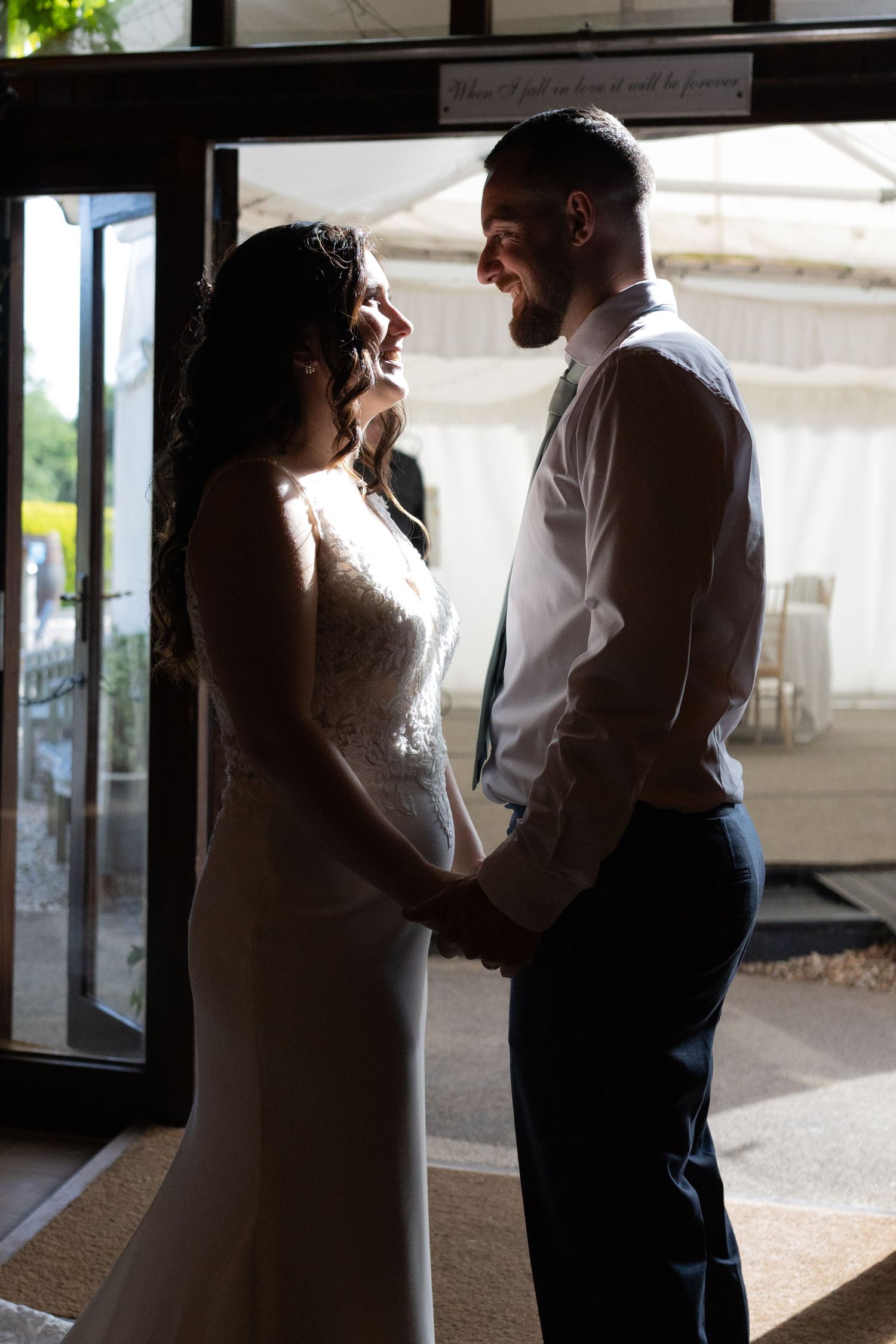Romantic silhouettes of a couple embracing in front of sunlit windows.