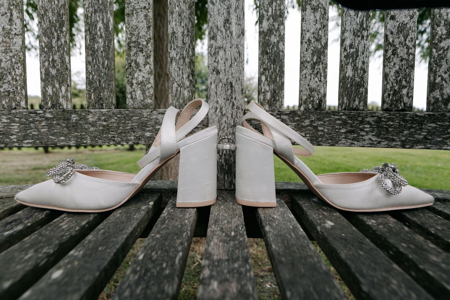 White bridal shoes displayed on a rustic wooden deck with natural lighting.