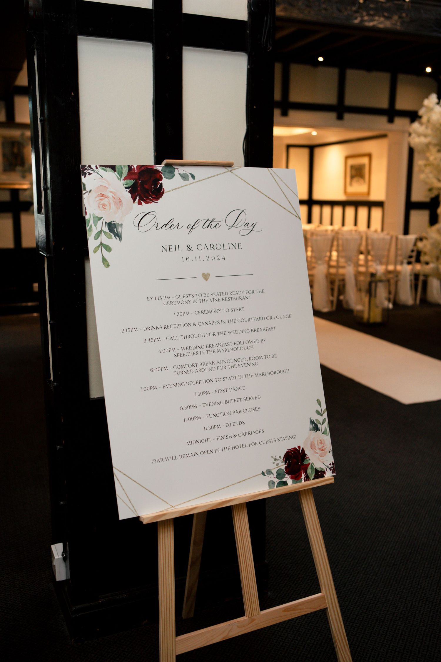 Wedding signage displays order of events on wooden easels with floral design accents.
