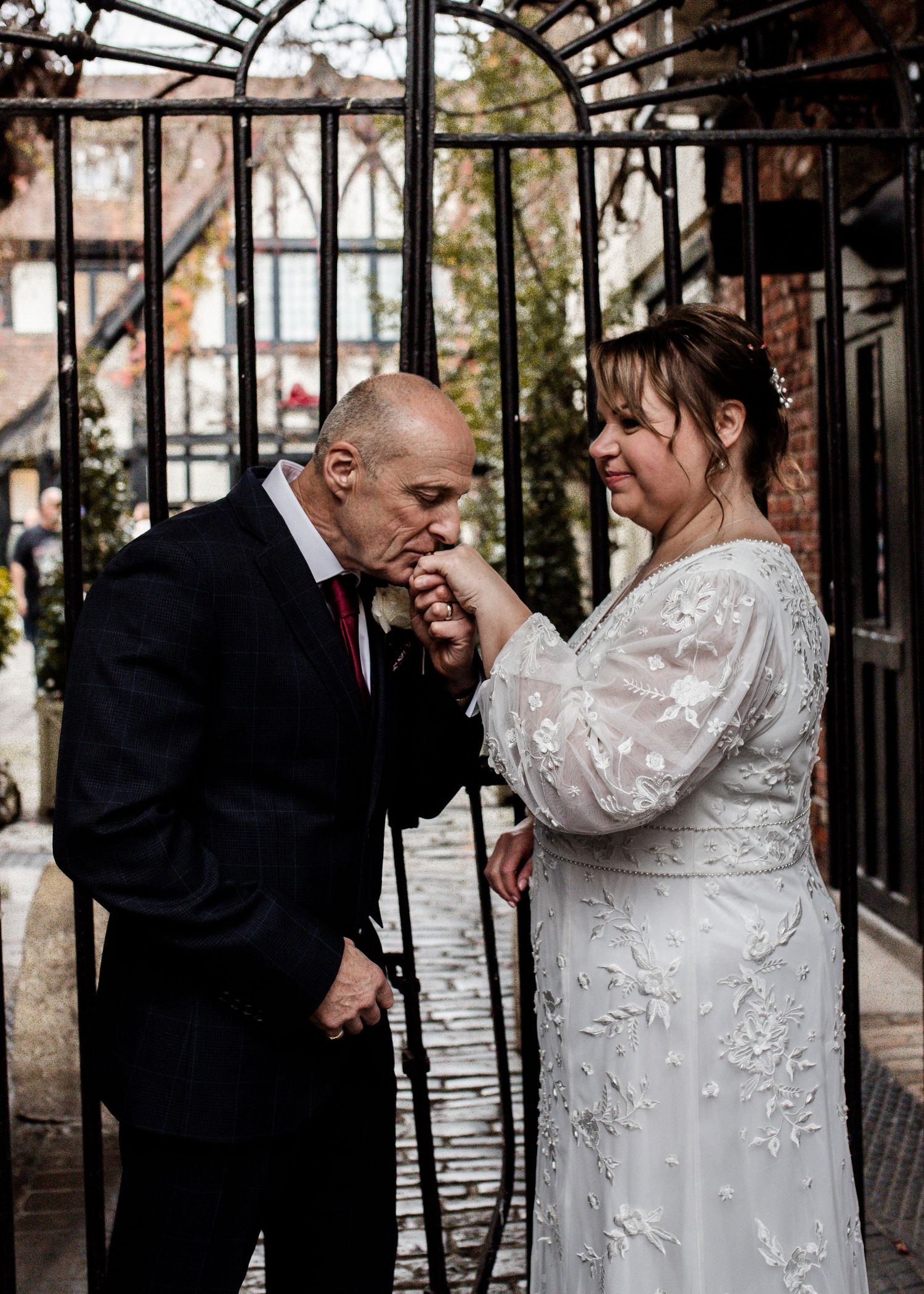 Wedding couple sharing playful moment under ornate iron archway.