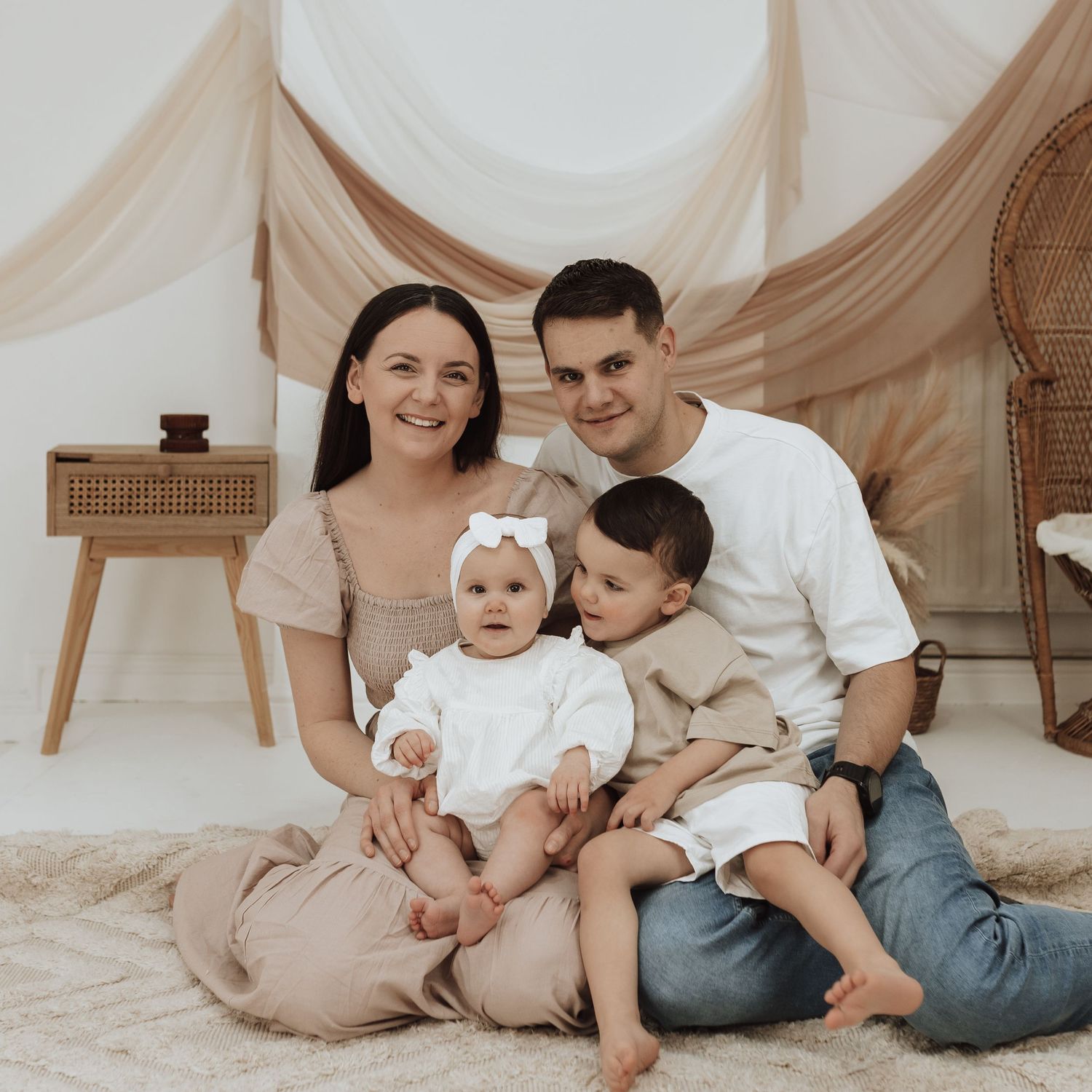 Family portrait session with neutral colors and soft lighting against a white backdrop.