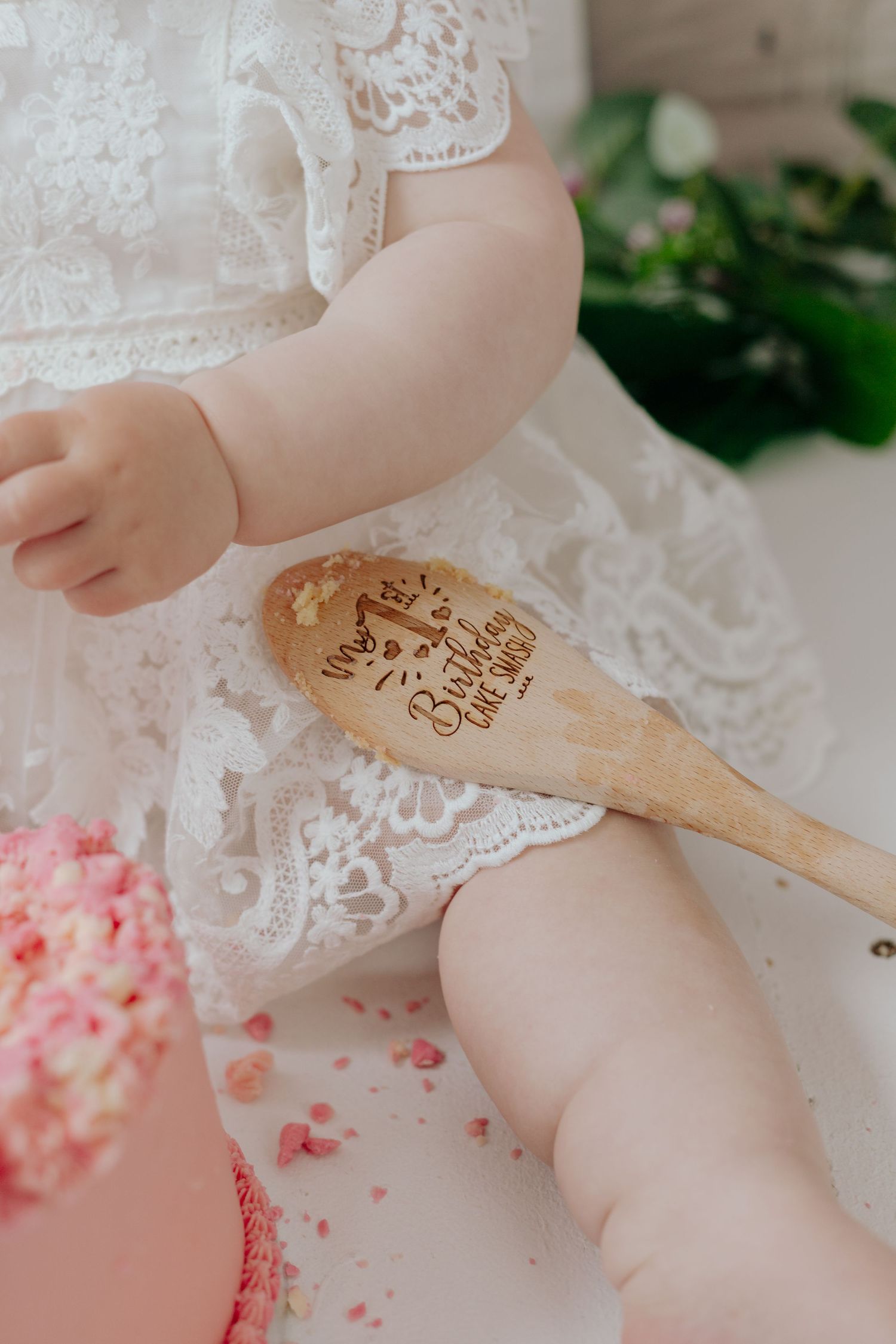 Detail shot of cake smash setup with wooden spoon and pink frosting.
