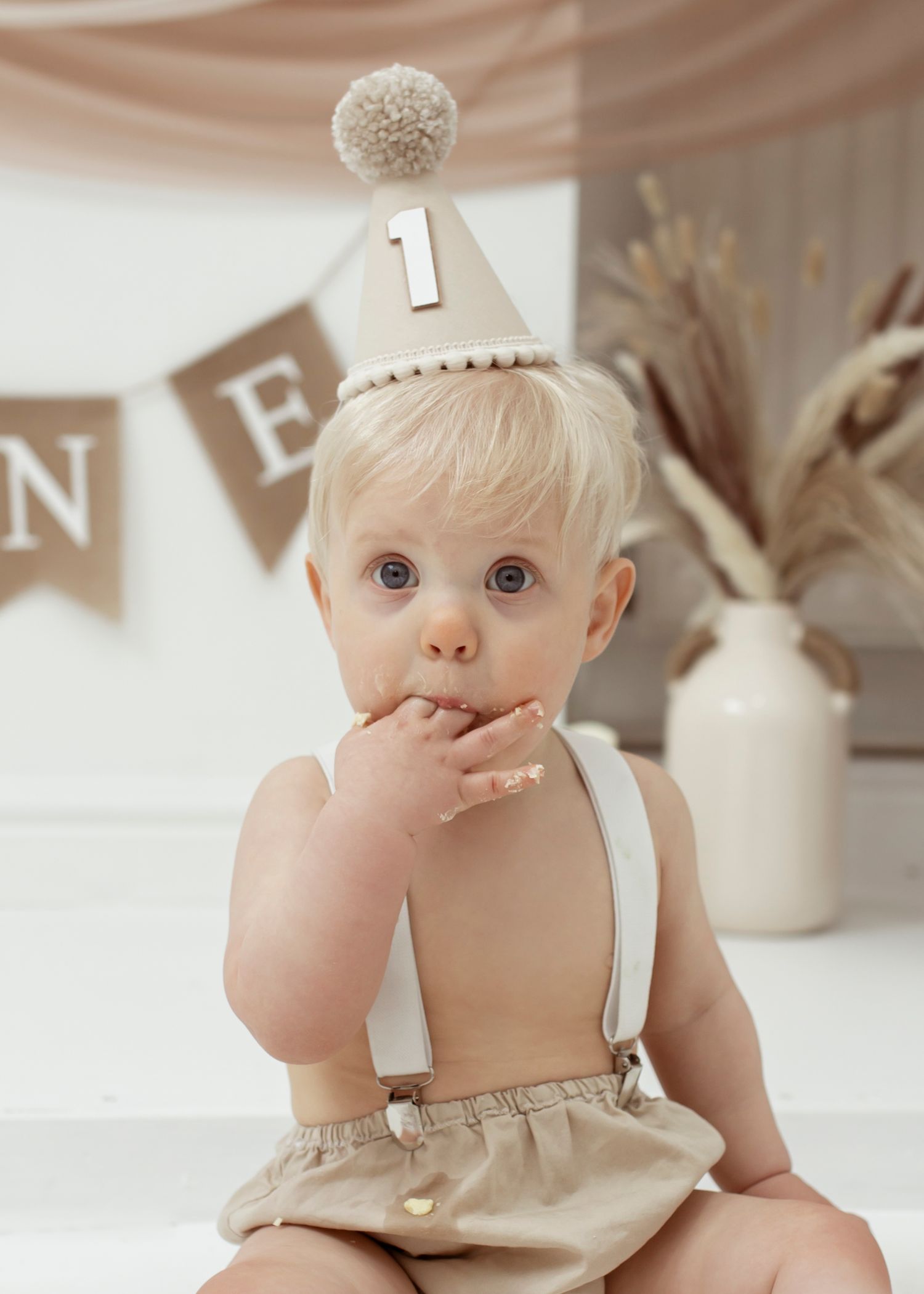 First birthday cake smash setup in neutral tones with rustic decorations.