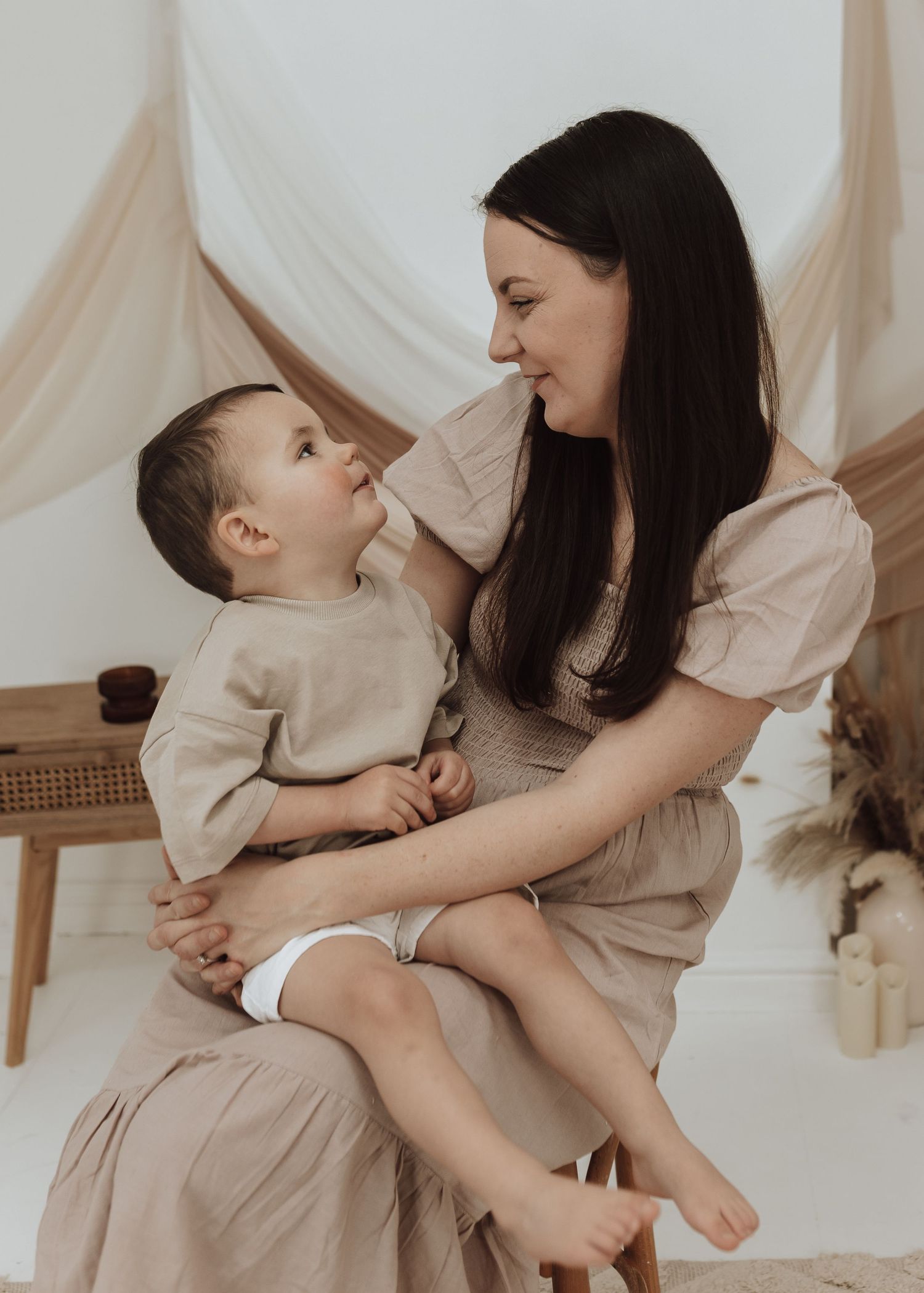 Intimate family portrait session showing tender moments in a neutral-toned studio setting.
