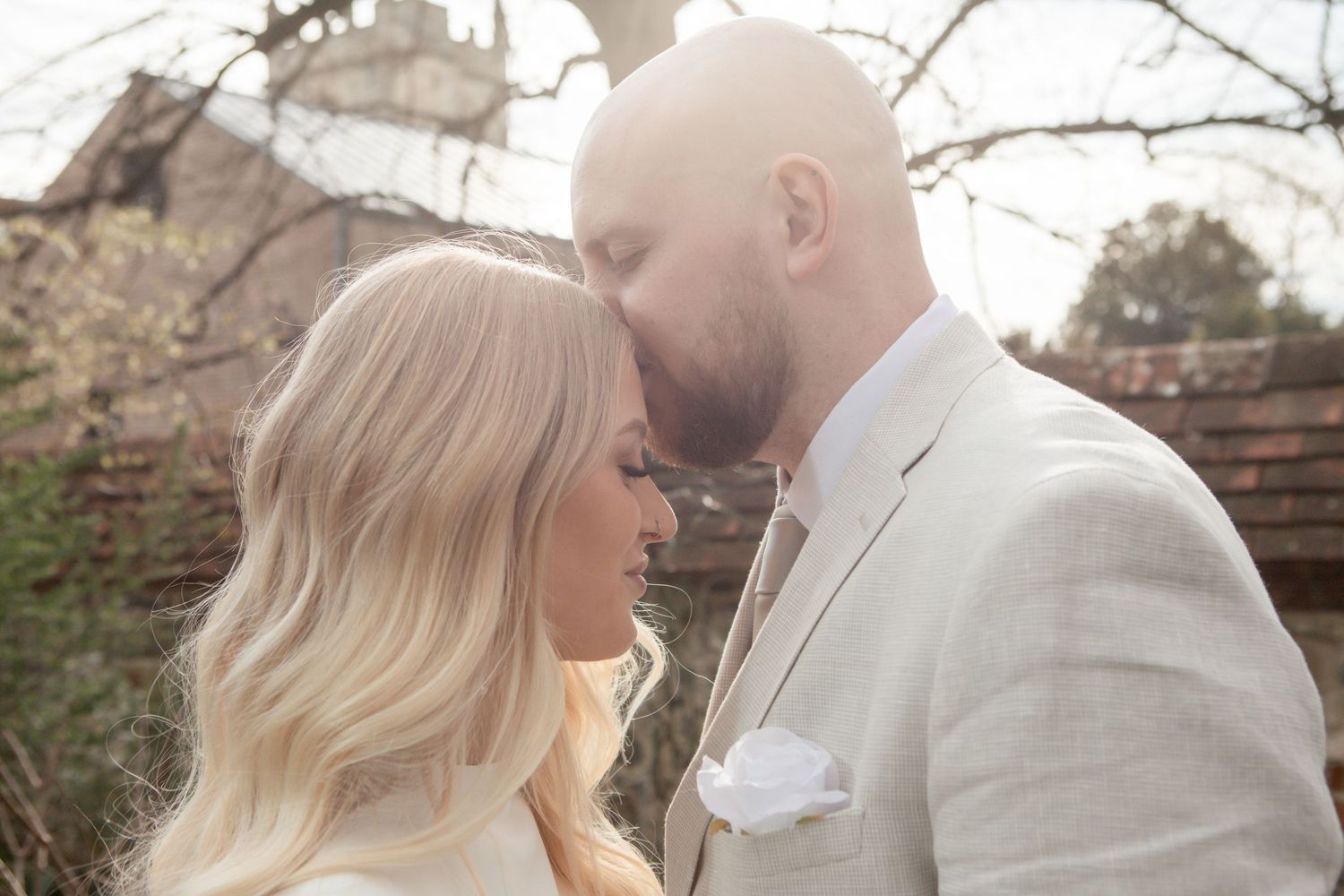 Close-up of a tender moment between a couple in white clothing outdoors.