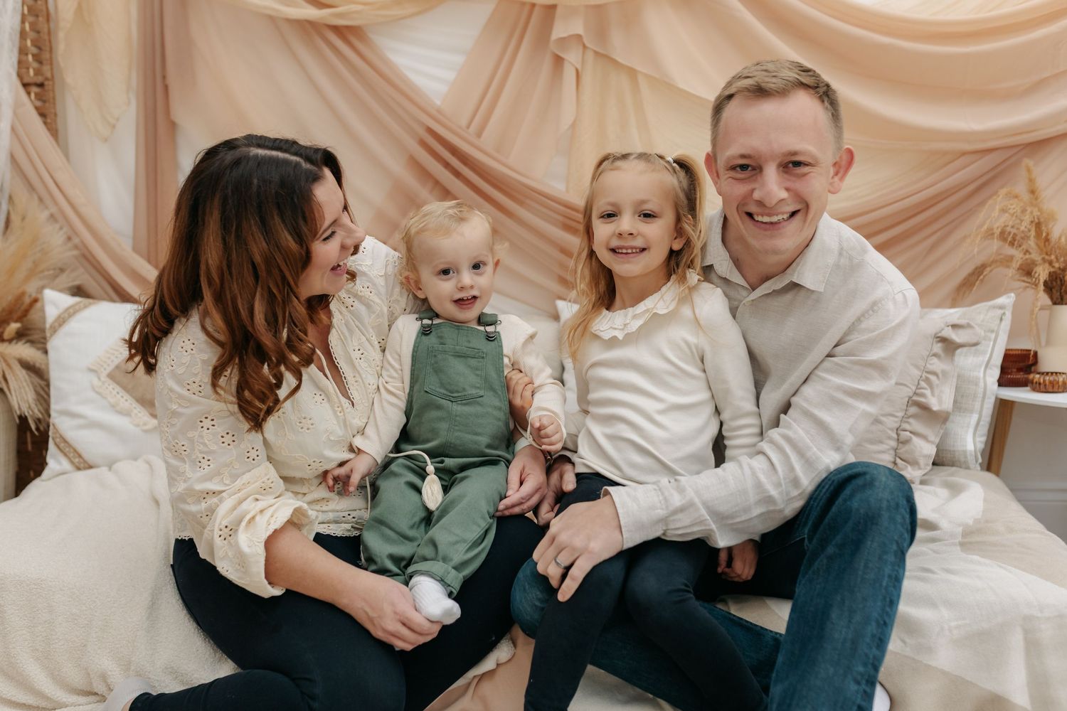 Family portrait session with neutral tones and draped fabric backdrop.