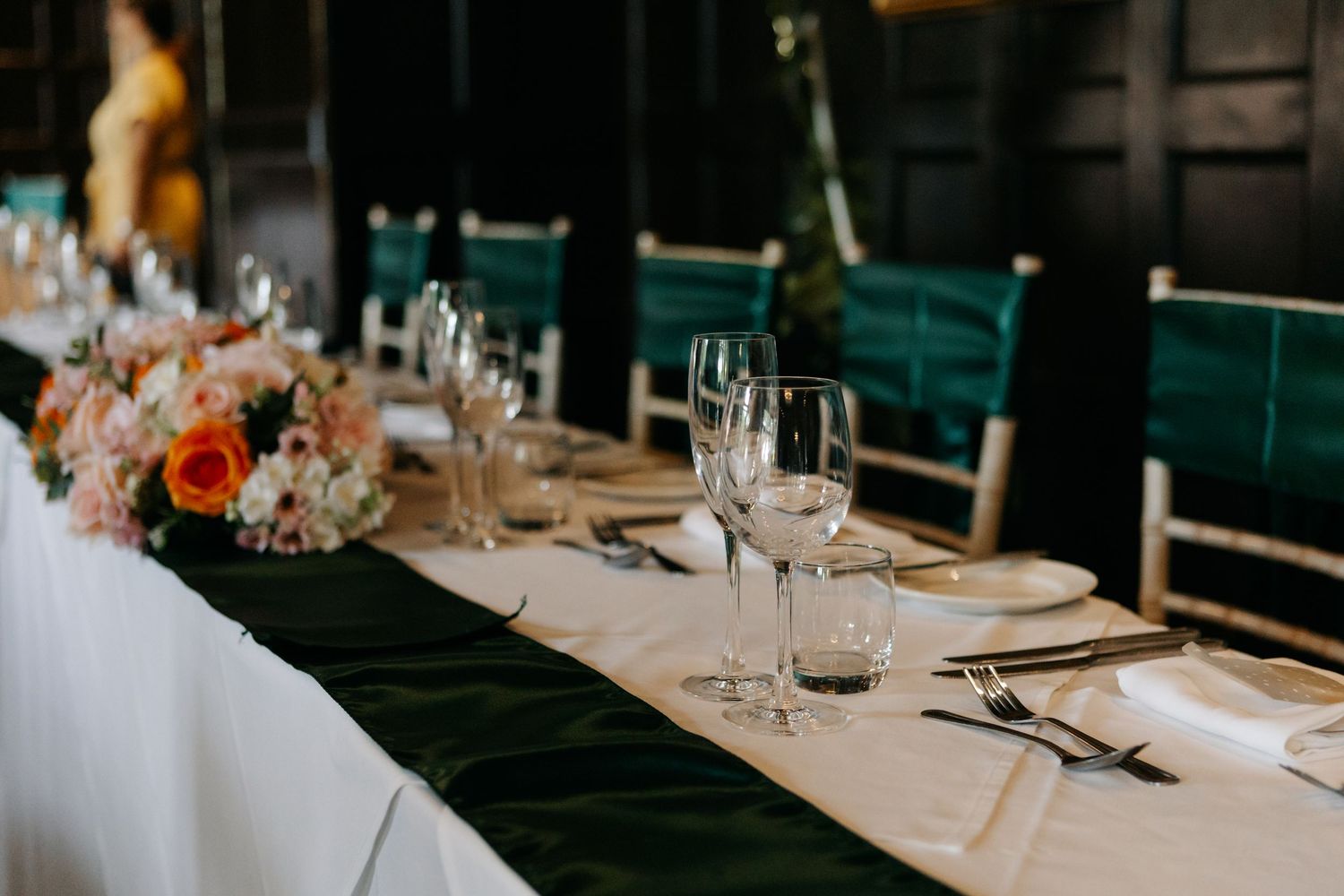 Elegant table settings at a wedding reception with white linens and floral centerpieces.