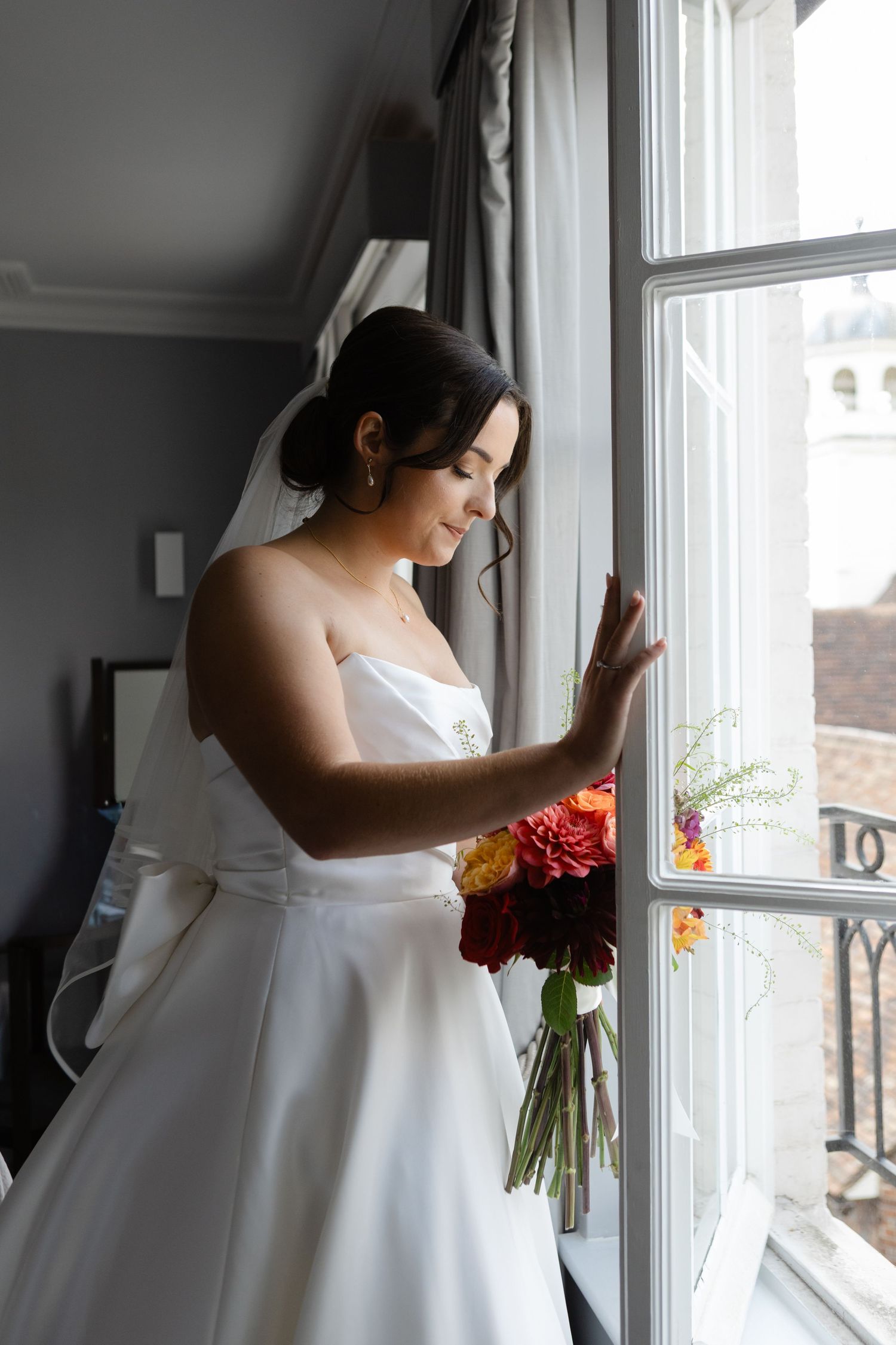 Elegant white wedding dress photographed near bright window with natural light.