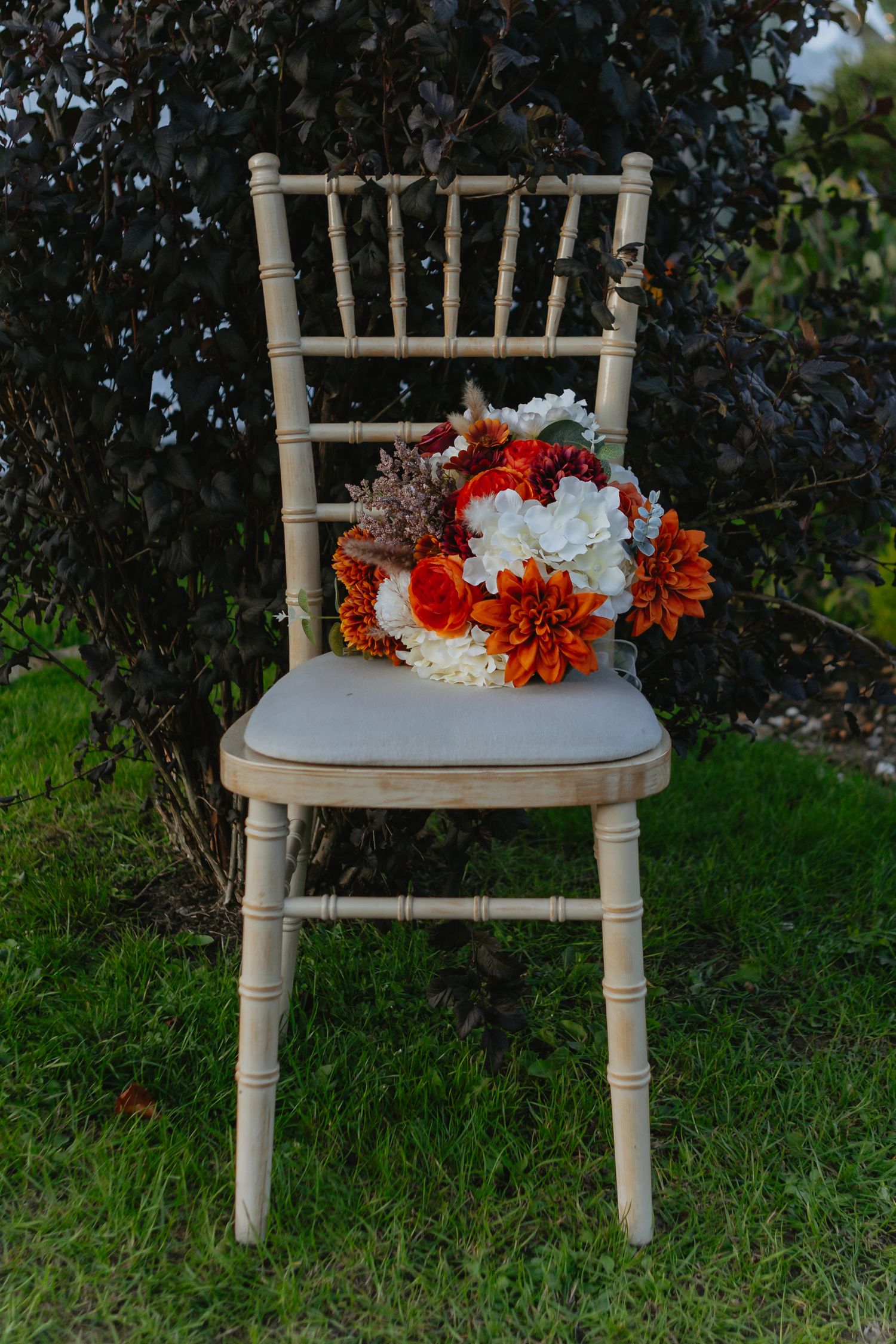 A vintage-style chair decorated with red and white floral arrangements in a garden setting.