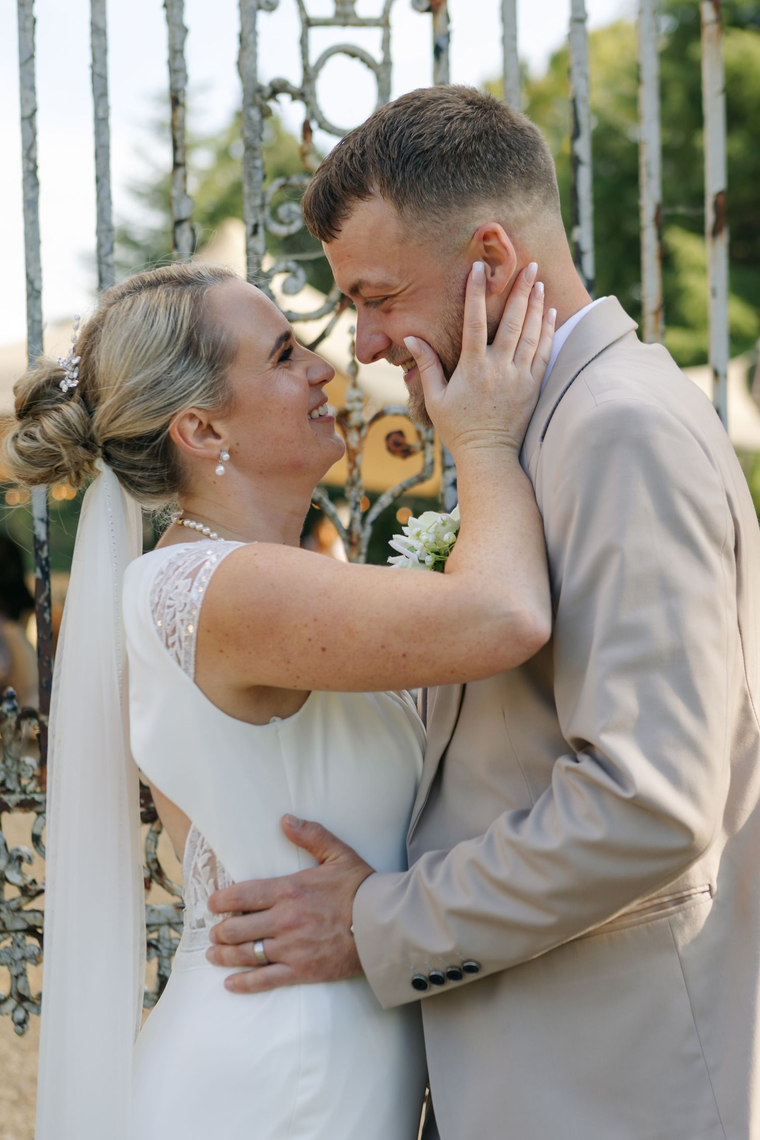 Intimate wedding portrait by decorative iron gates showing a tender embrace.