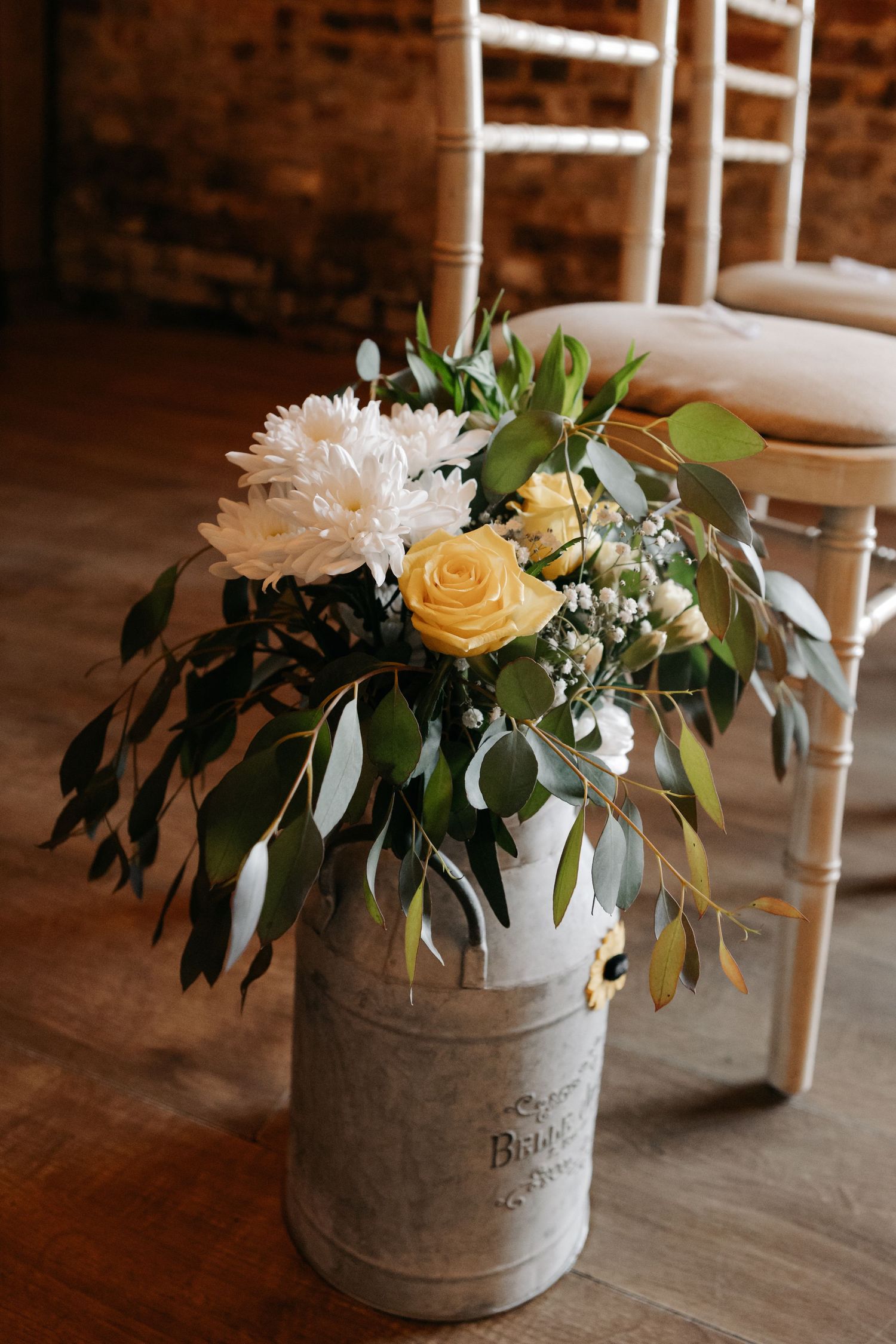 Rustic floral arrangements in vintage metal containers with yellow roses and greenery.