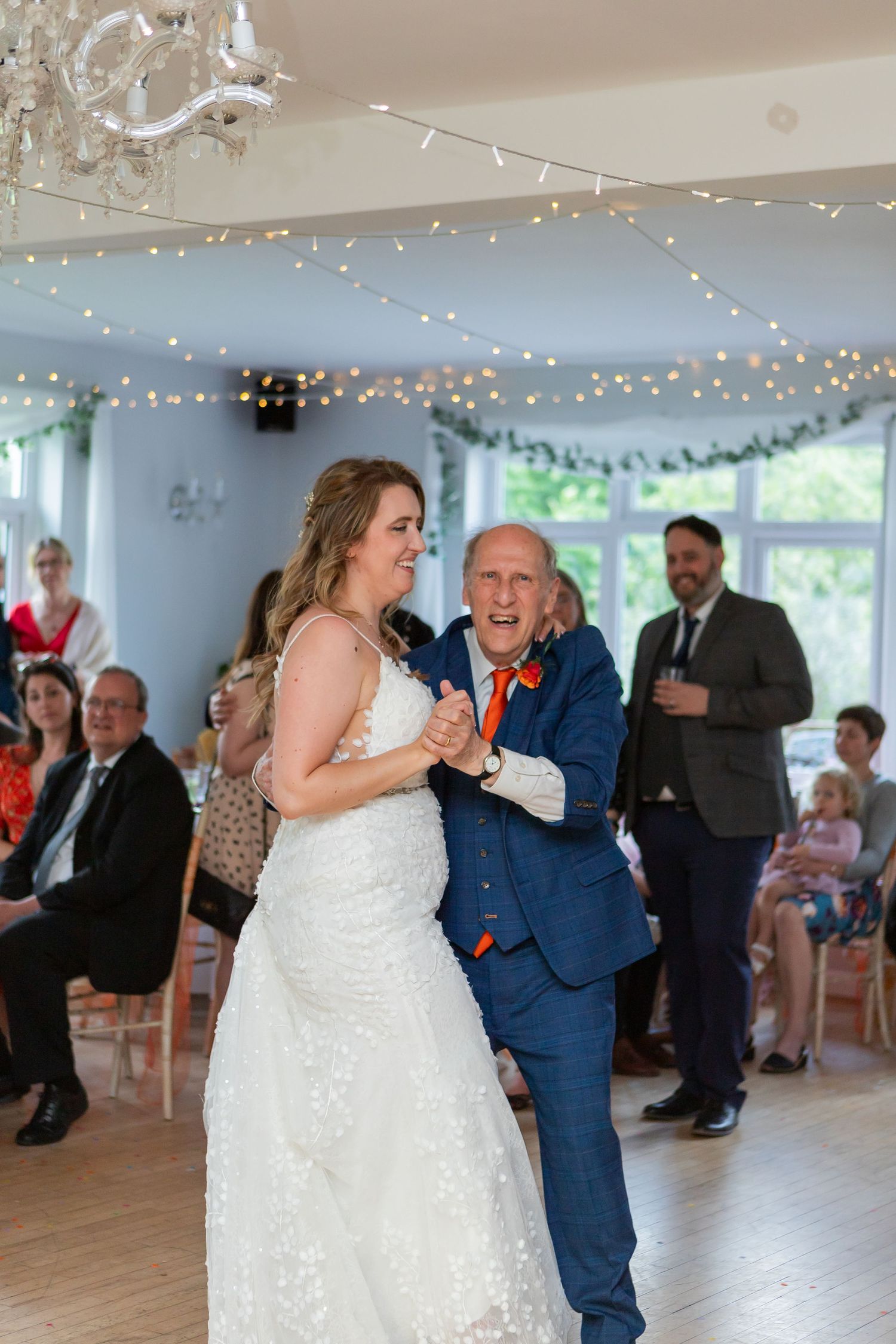 Joyful dance moment captured under twinkling lights during wedding reception.