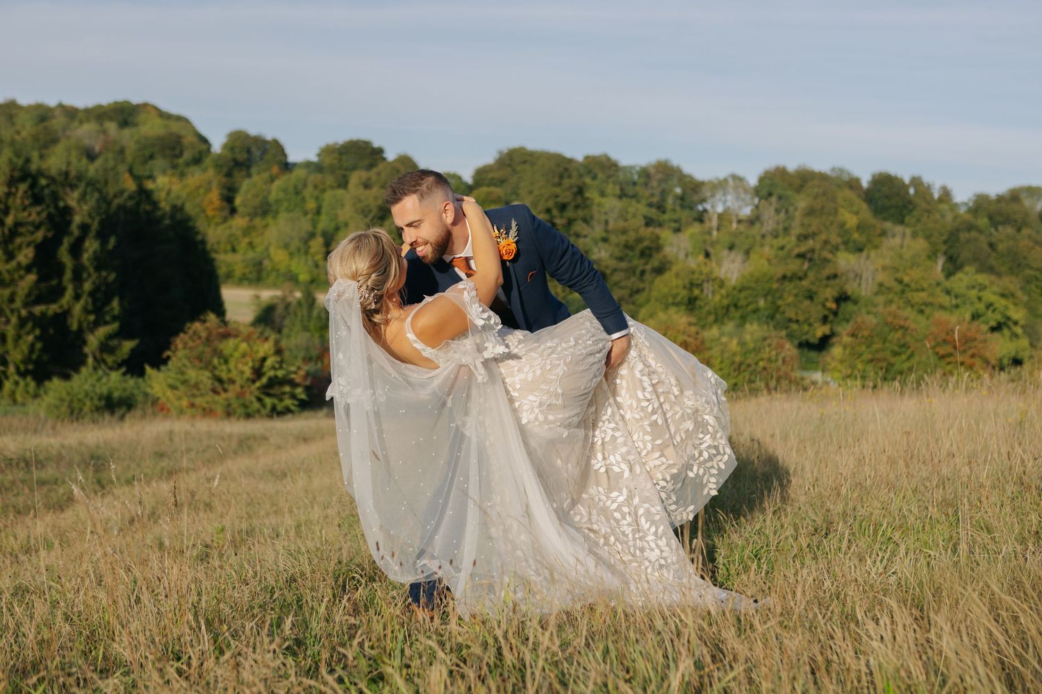 A romantic dip pose in a grassy field with the bride's dress flowing.