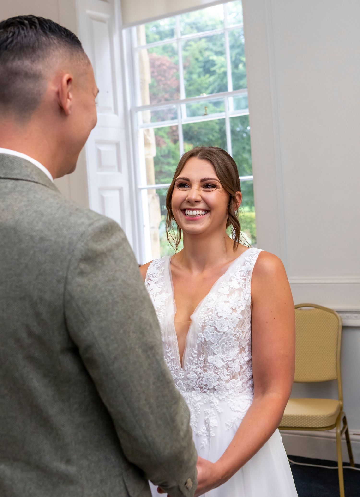 Wedding couple sharing a joyful moment in a bright indoor setting.