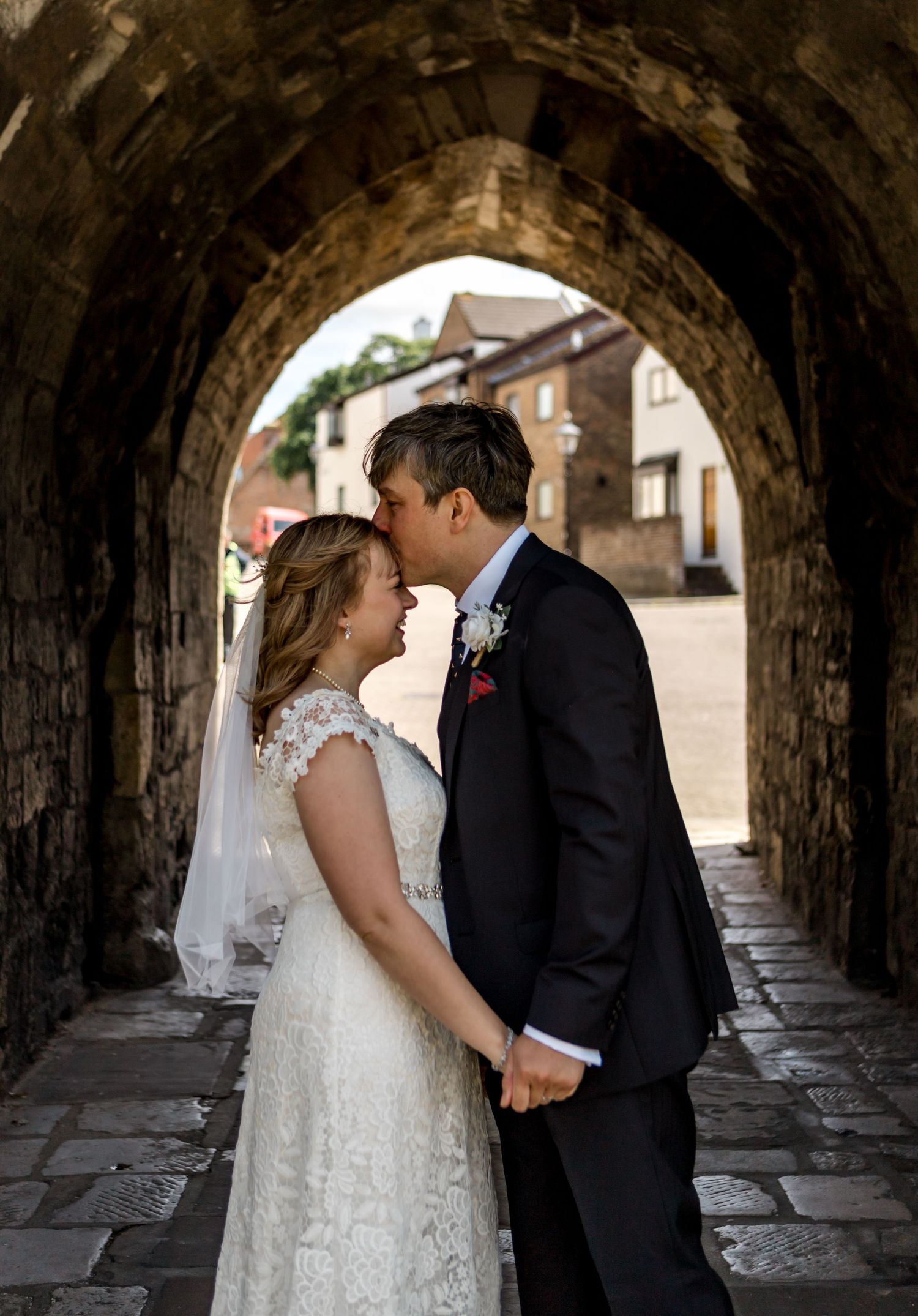 An intimate wedding moment shared under a historic stone archway.