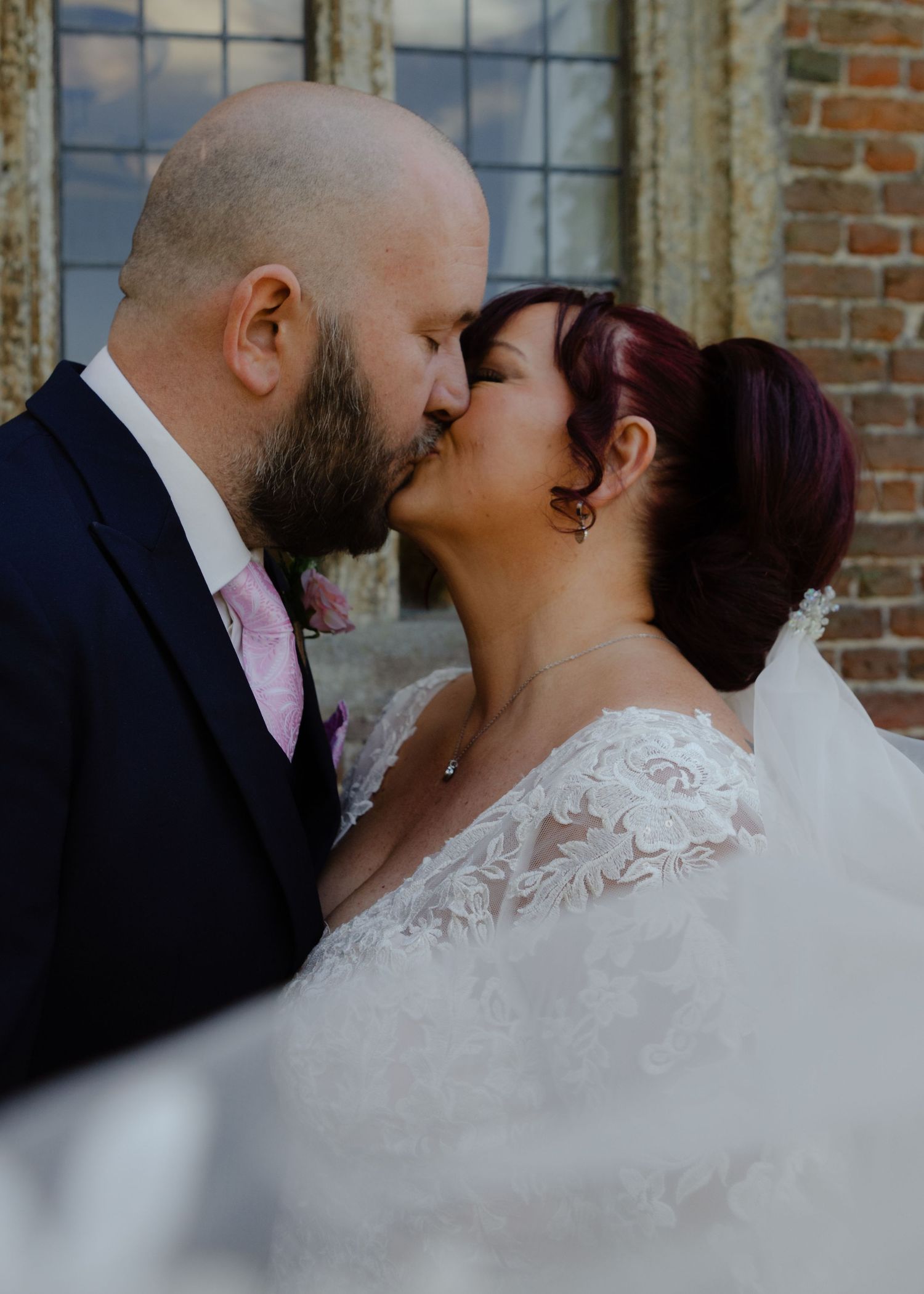 Romantic wedding couple sharing intimate moments in vintage brick building.