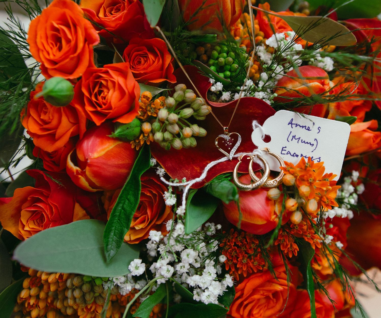 Vibrant orange roses and greenery create stunning wedding floral arrangement.