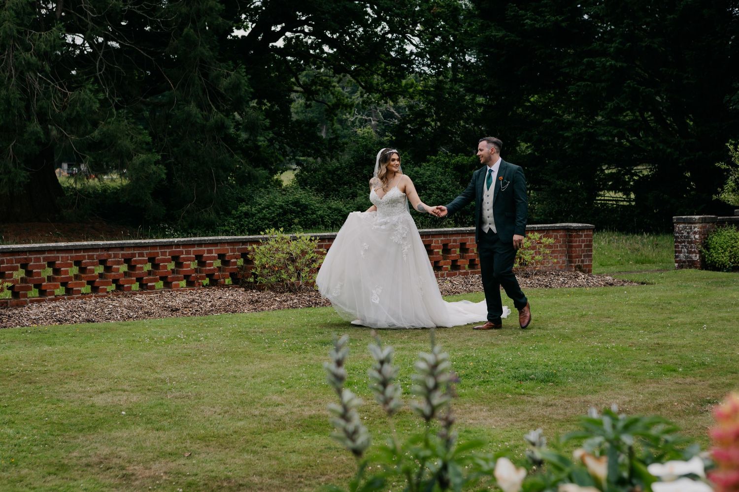 A couple walks together on a garden path surrounded by lush greenery.