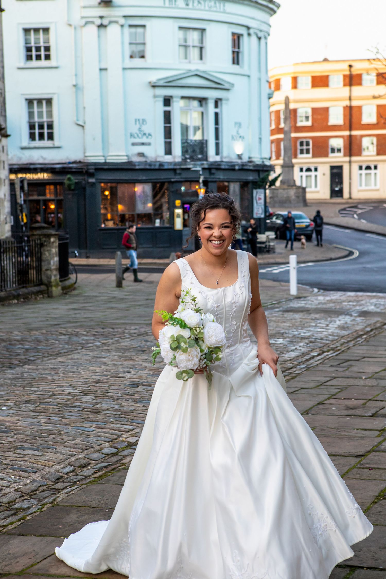 Bride in a classic white ballgown poses on cobblestone streets near historic buildings.