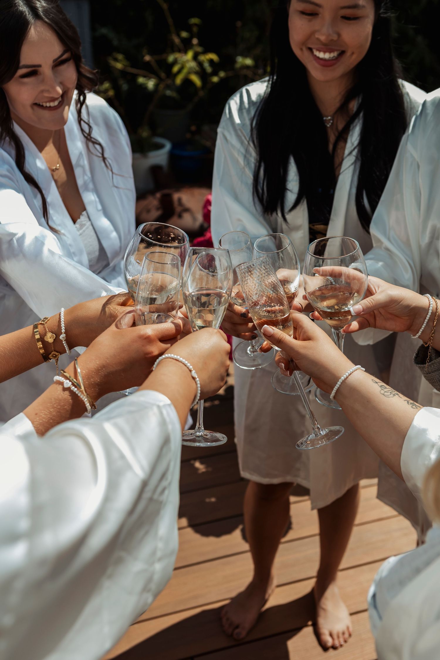 Hands raise champagne glasses in a celebratory toast while wearing white robes.