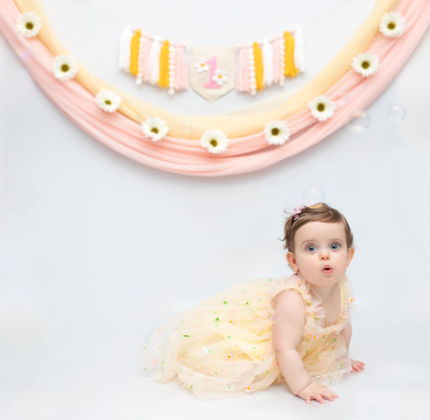 Baby posing during cake smash session with pink and yellow party decorations.