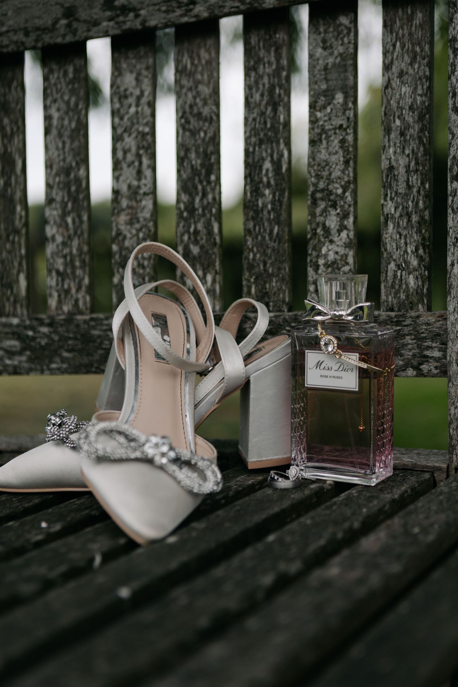 Wedding accessories including bridal shoes and jewelry arranged on a wooden bench.