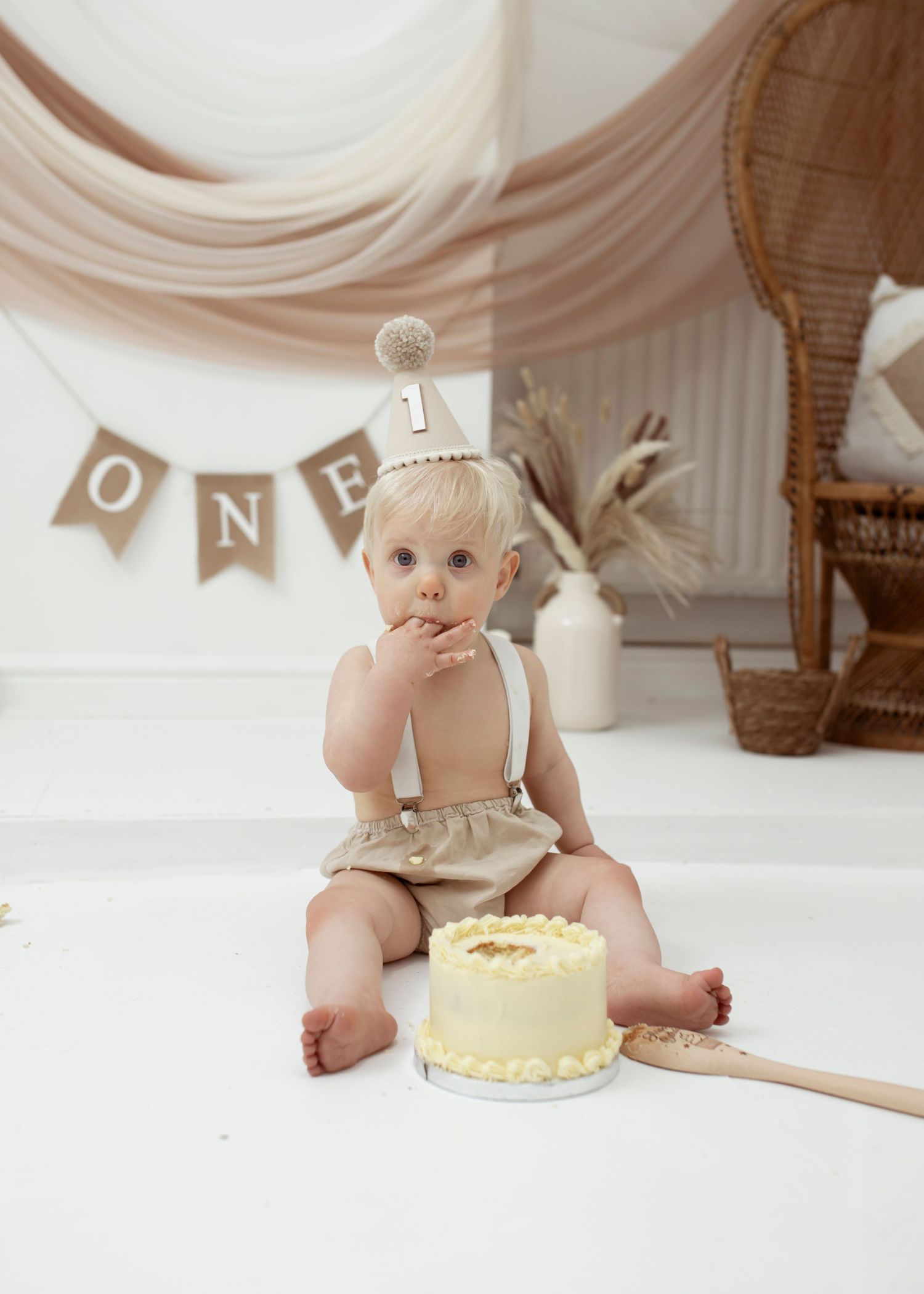 Rustic first birthday setup with cake, wooden spoon, and banner decorations.