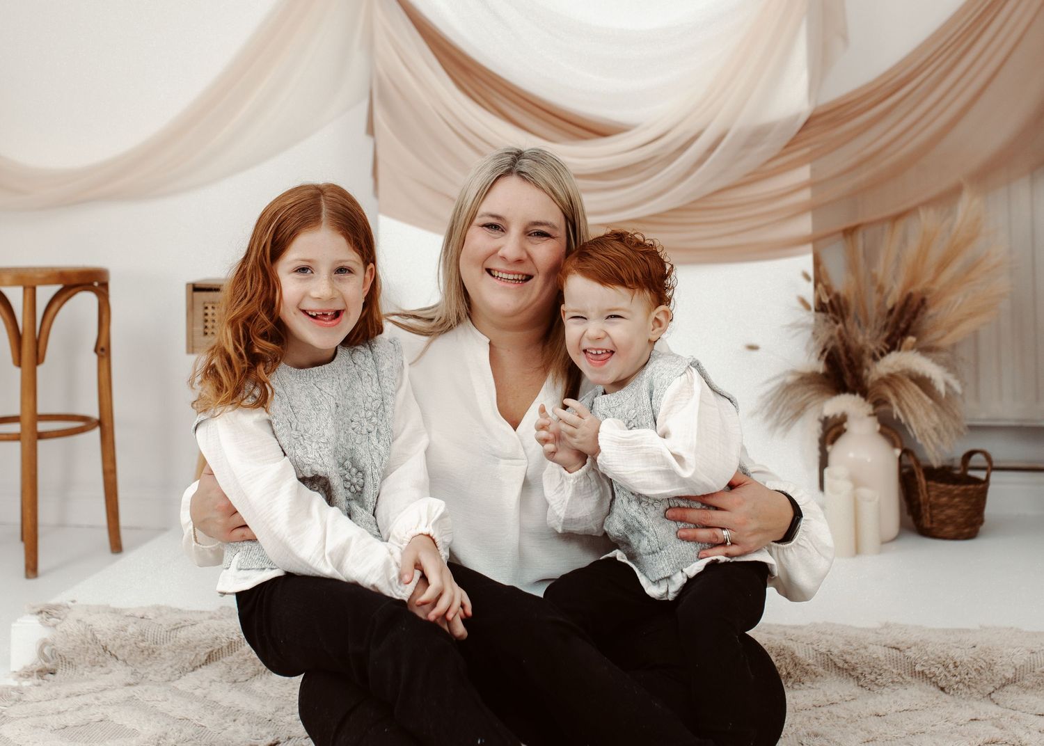 Candid family photo session with coordinated outfits against a light neutral backdrop.