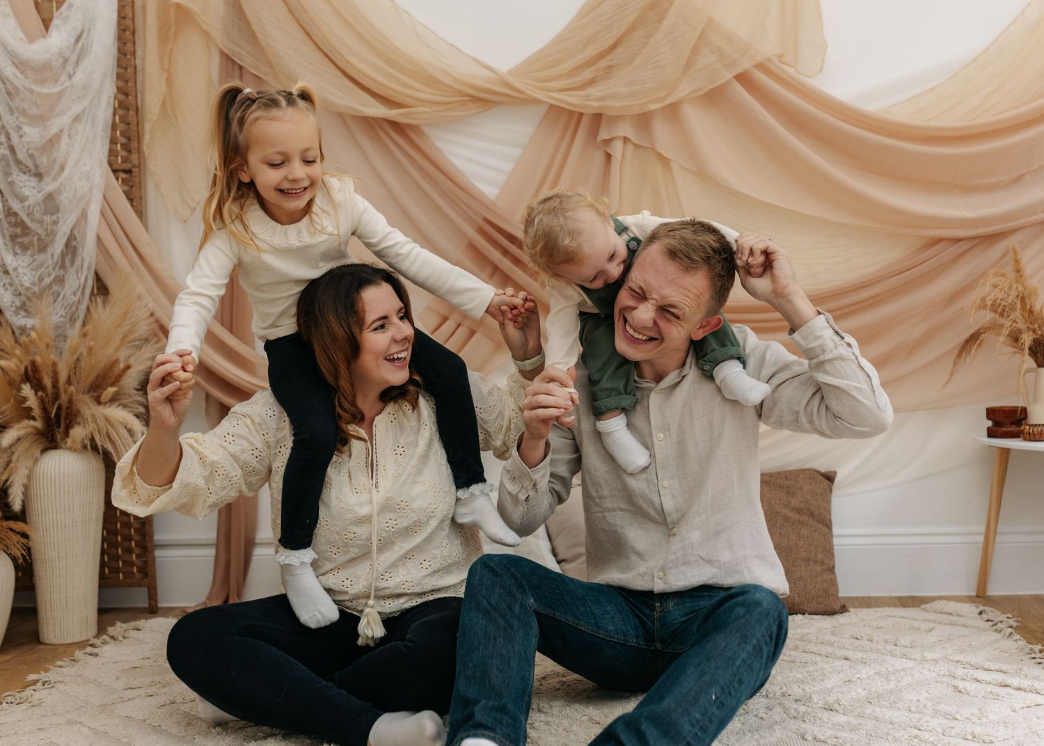Joyful family laughing together on floor during photo session.