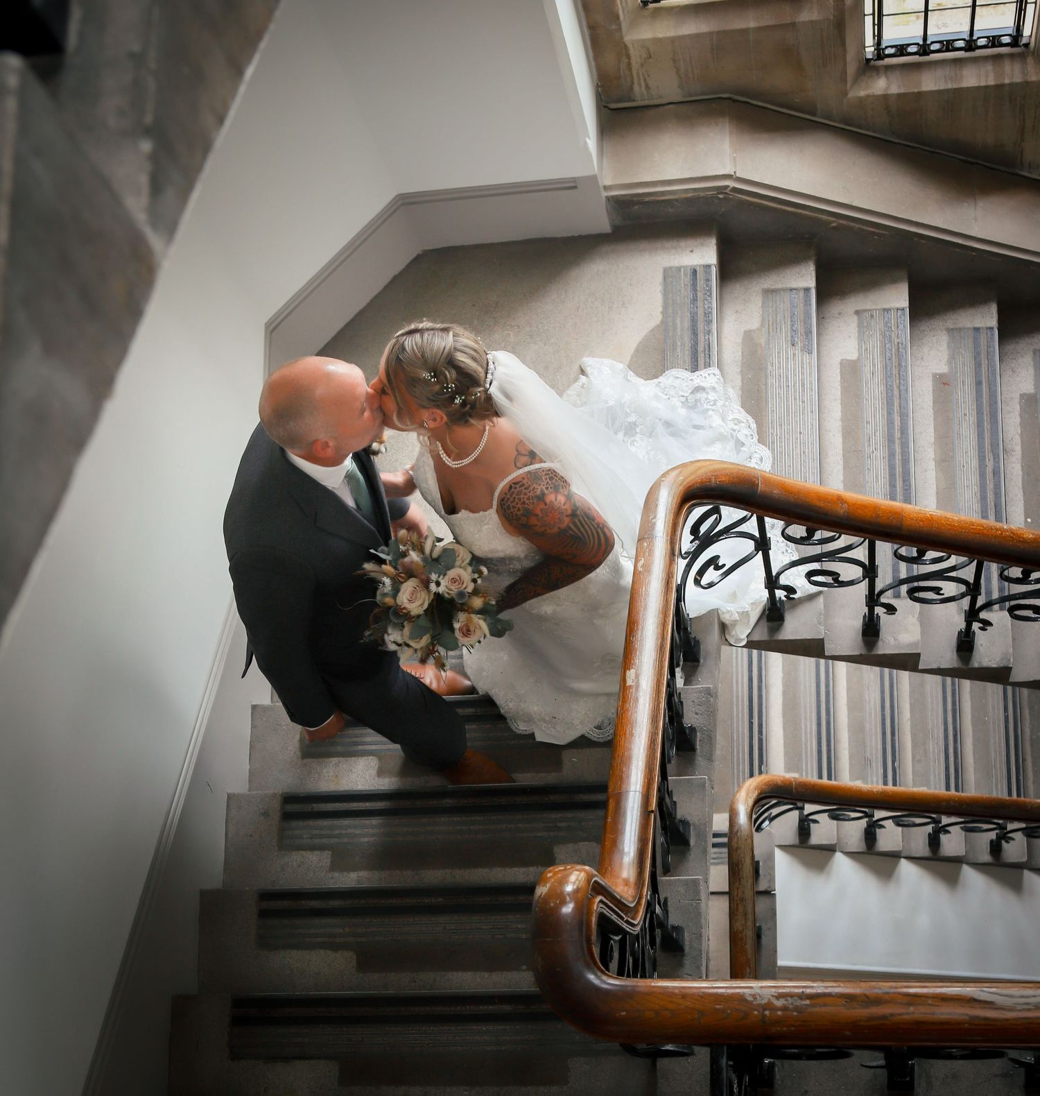 Romantic couple portraits on historic staircase with dramatic lighting.