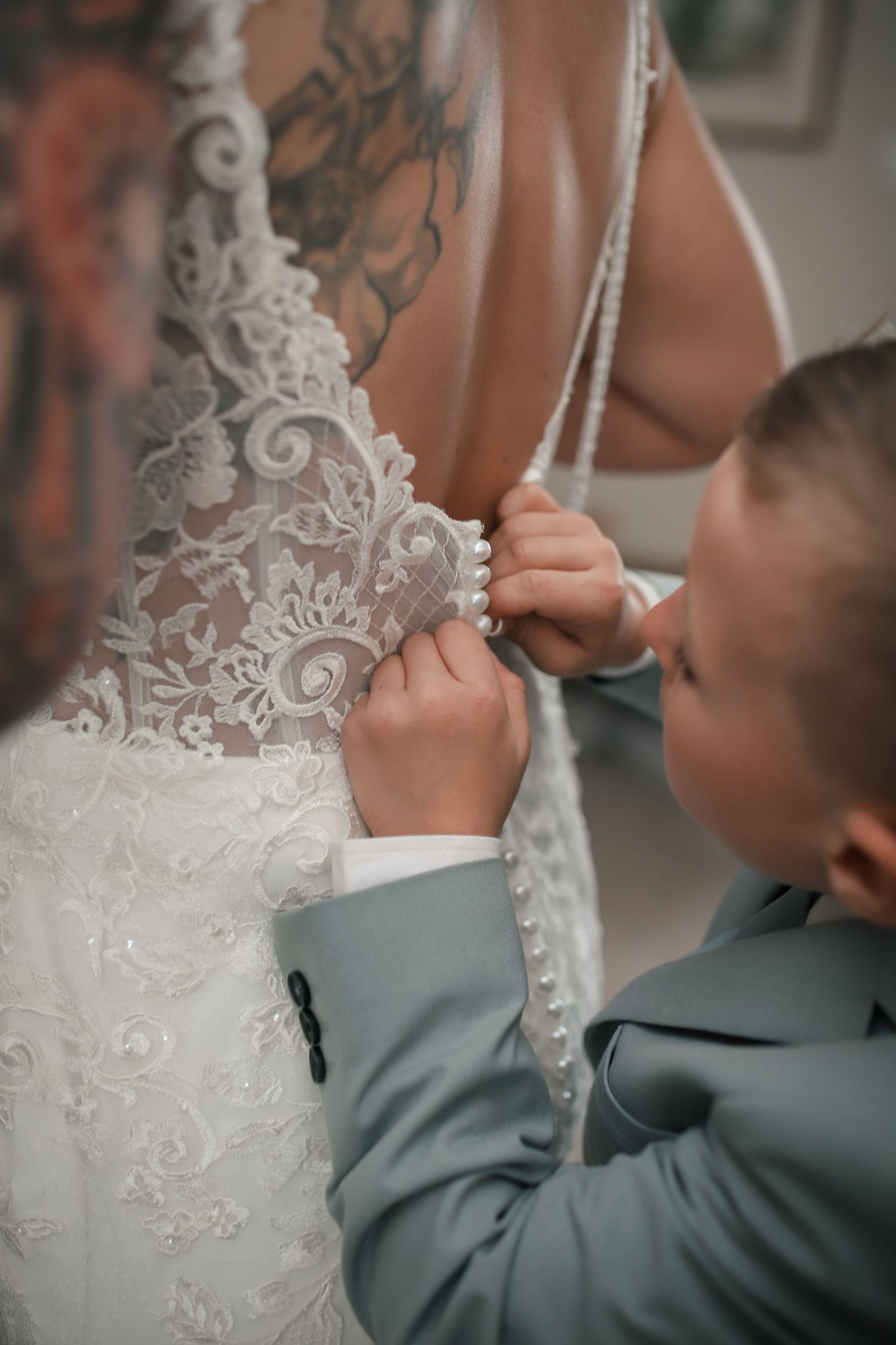 Close-up detail of intricate lace wedding dress being fastened.