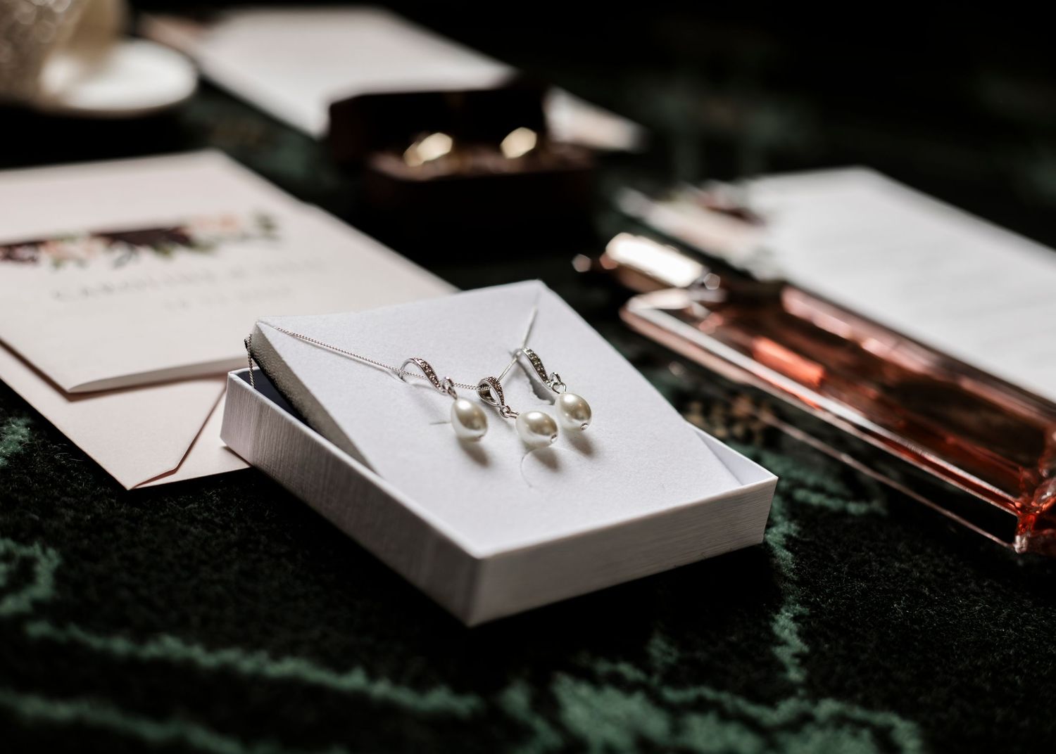 Wedding accessories and paper goods artistically arranged on dark surface.