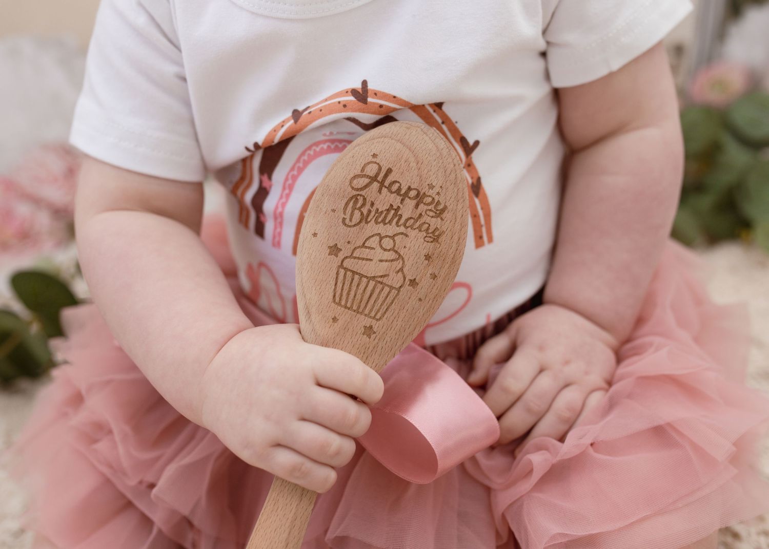 Wooden spoon with cupcake design held during cake smash photography session.