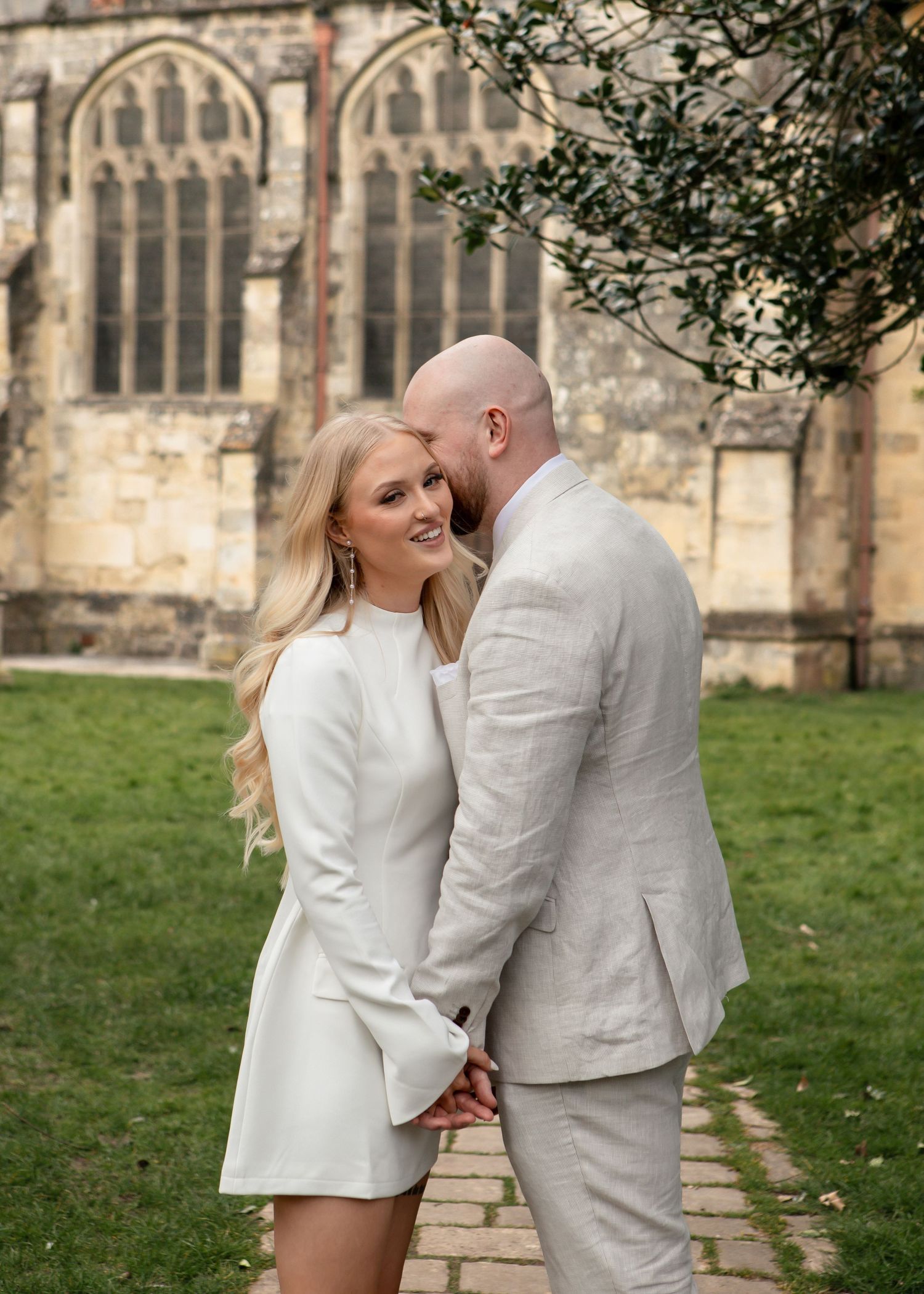 Romantic wedding photos captured outside historic church with couple in white and light gray.