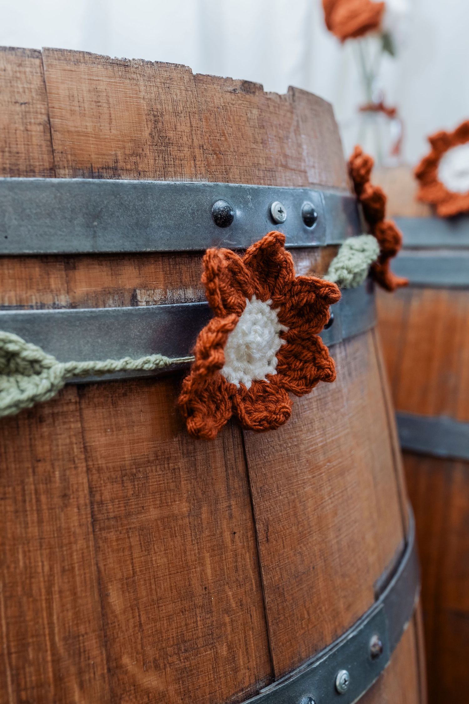 Rustic wooden barrel detail with orange floral decorations at a wedding venue.