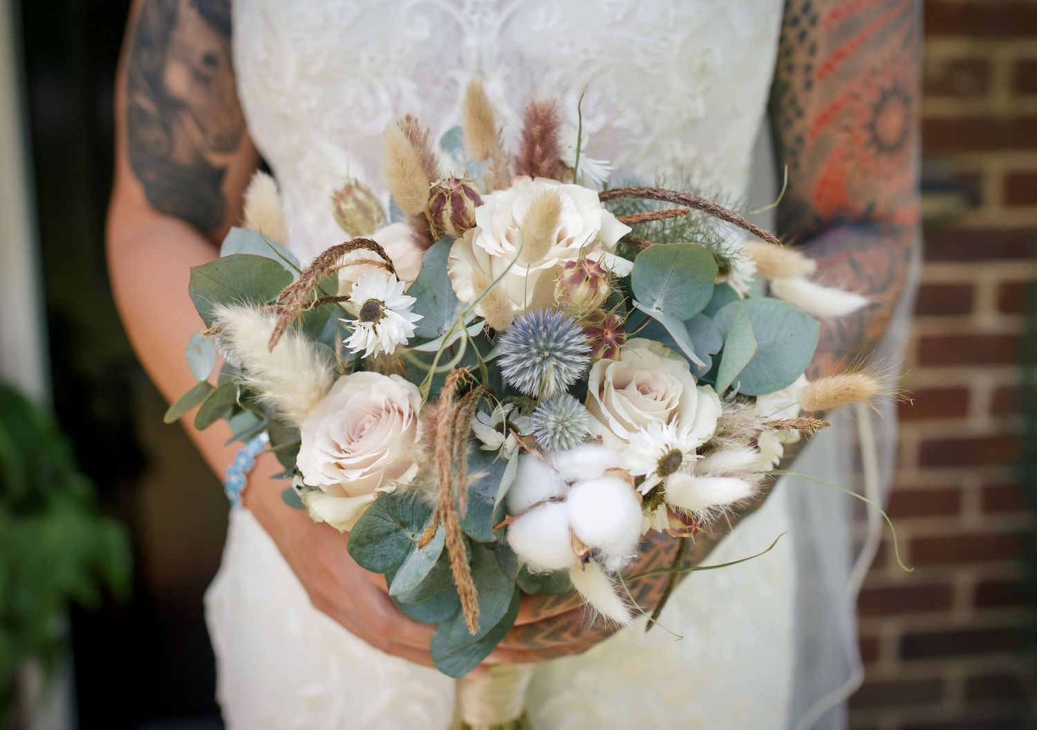 Bridal bouquet featuring white roses, cotton stems, and eucalyptus leaves.