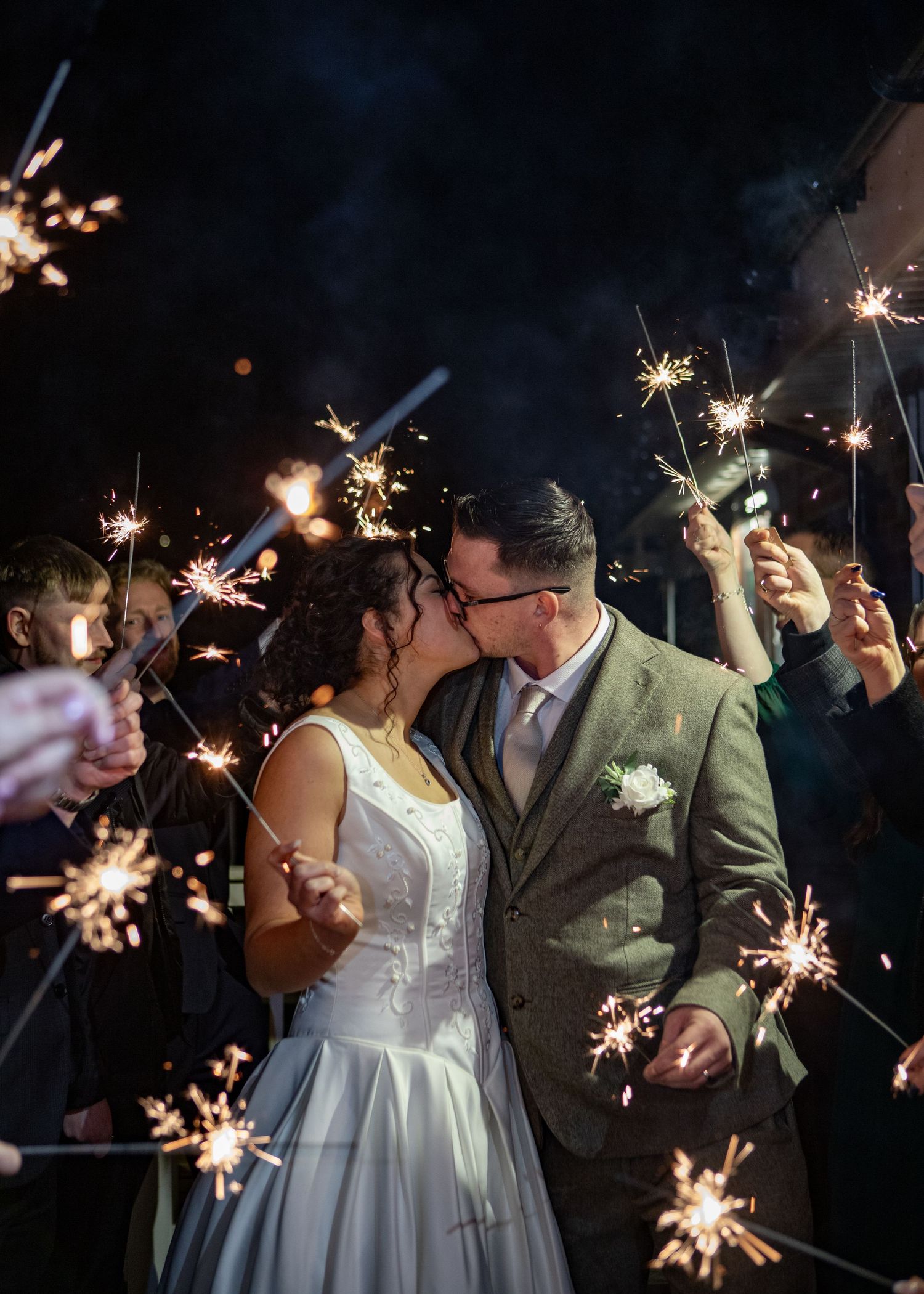 Newlyweds celebrate with sparklers during their nighttime wedding reception.