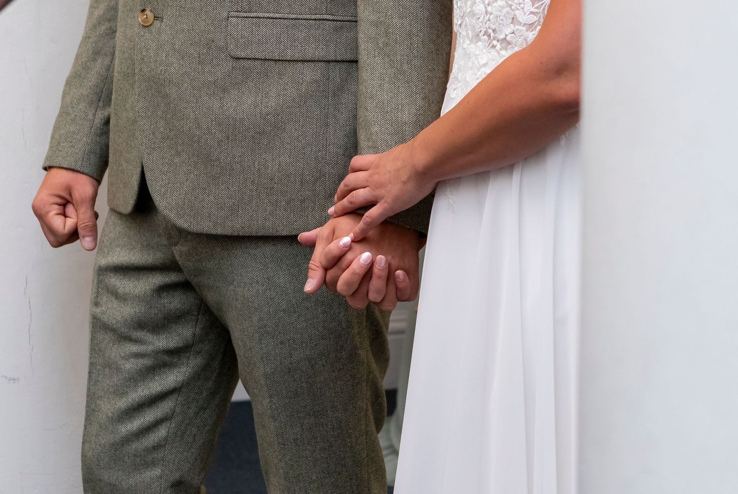 Detail shot of formal gray suit and white dress at a wedding ceremony.