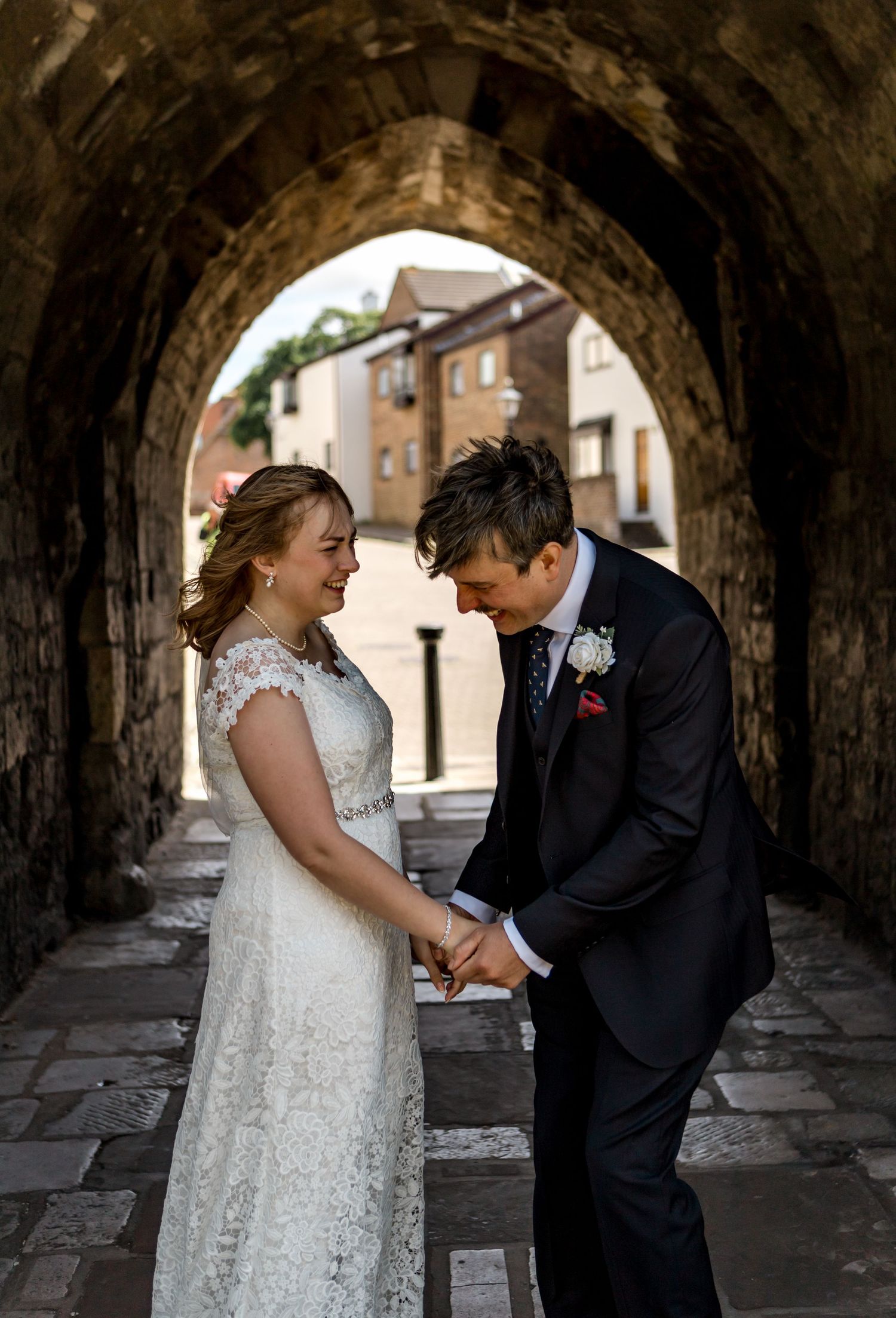 A romantic moment captured under a stone archway with a couple in wedding attire.