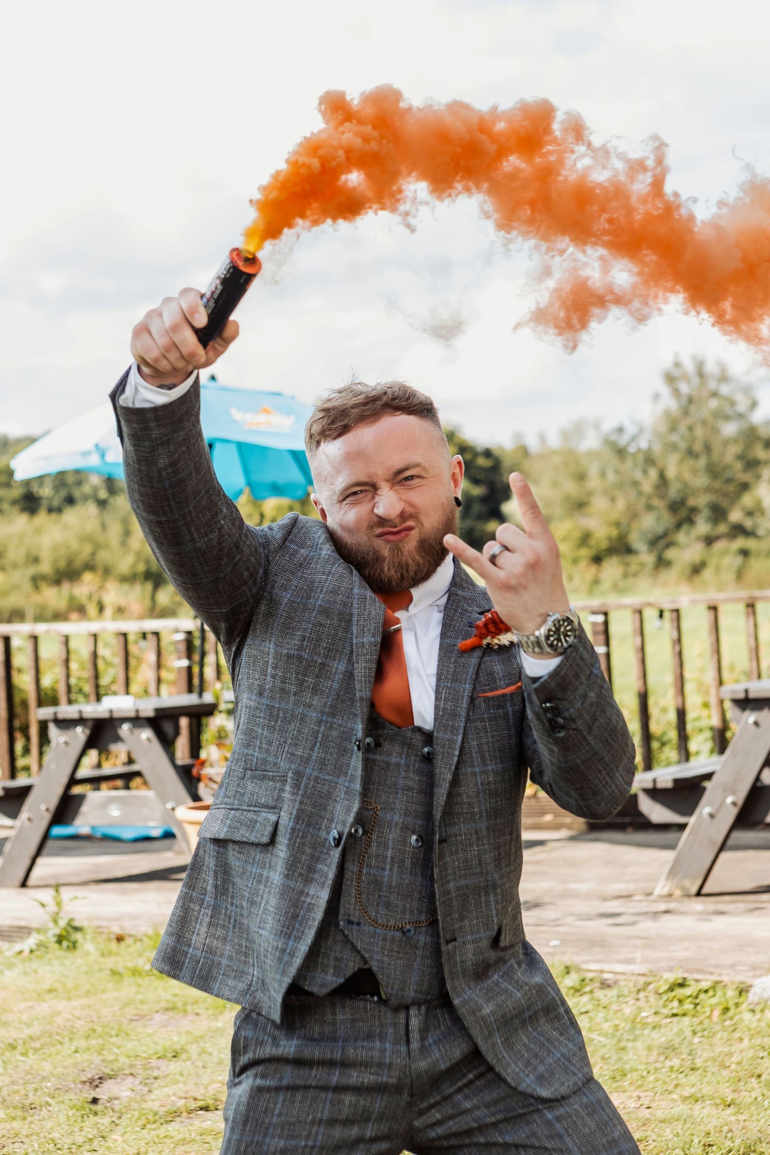 Celebratory moment with orange smoke bombs creating dramatic effects at an outdoor wedding.