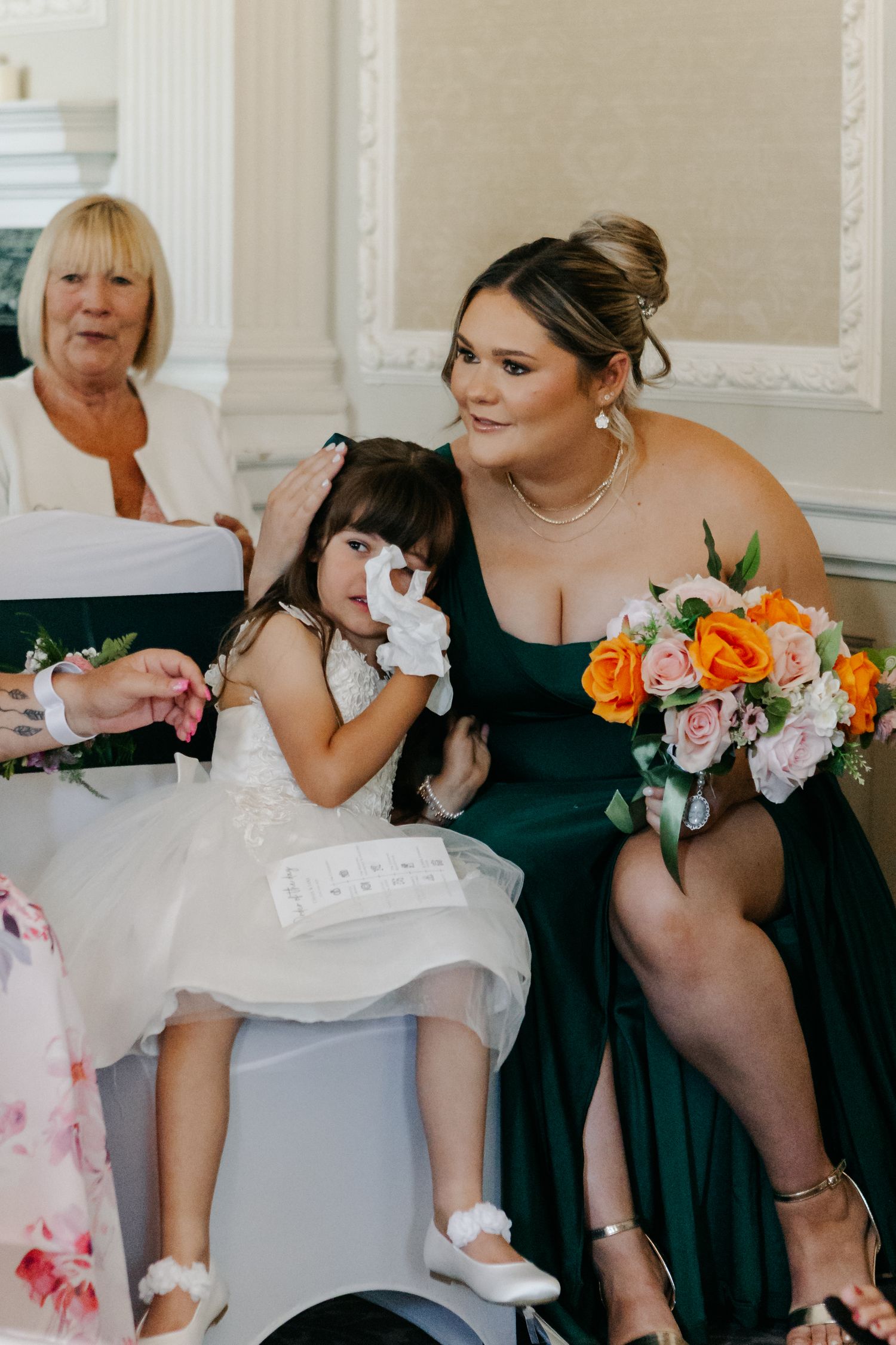 Wedding party in black dresses and white gown sitting together.