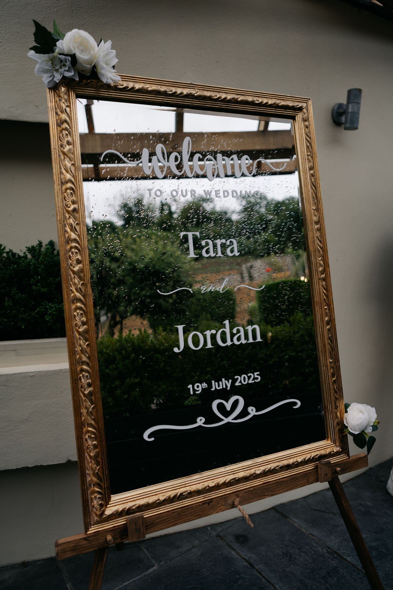 Elegant gold-framed wedding welcome sign displaying 'Tara & Jordan' with the date July 19th 2025.