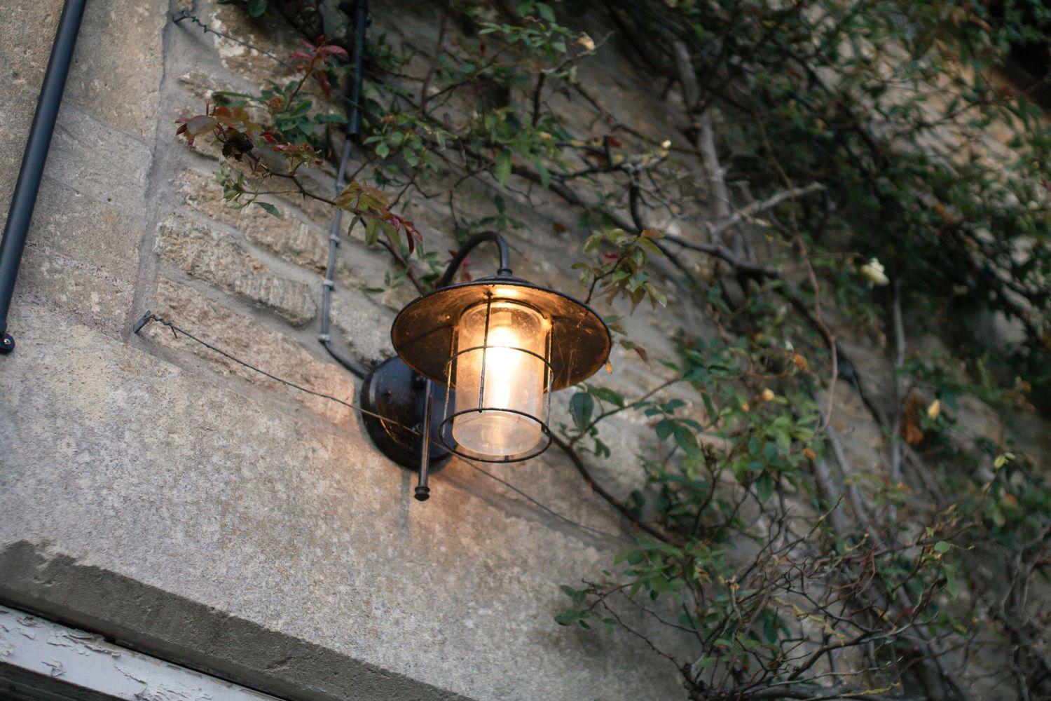 Outdoor wedding venue features rustic stone walls with decorative lighting.