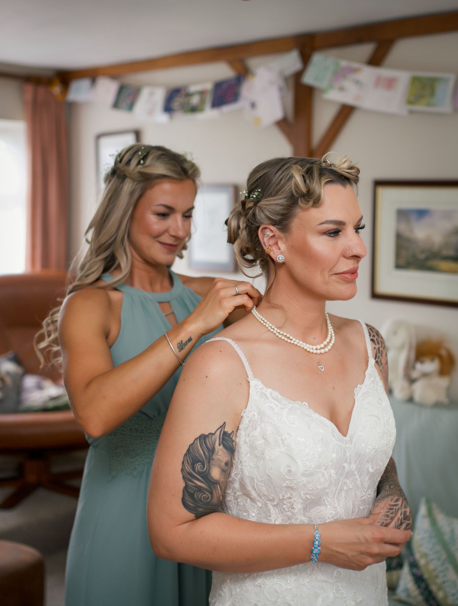 Wedding preparation scene with bridesmaids assisting in a rustic indoor setting.
