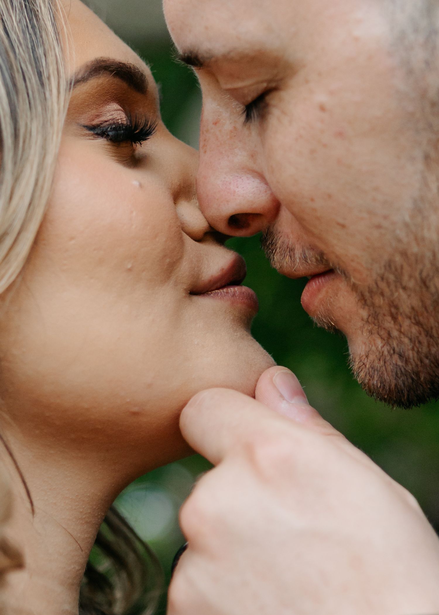 Close-up romantic moment between newlyweds in an outdoor setting.