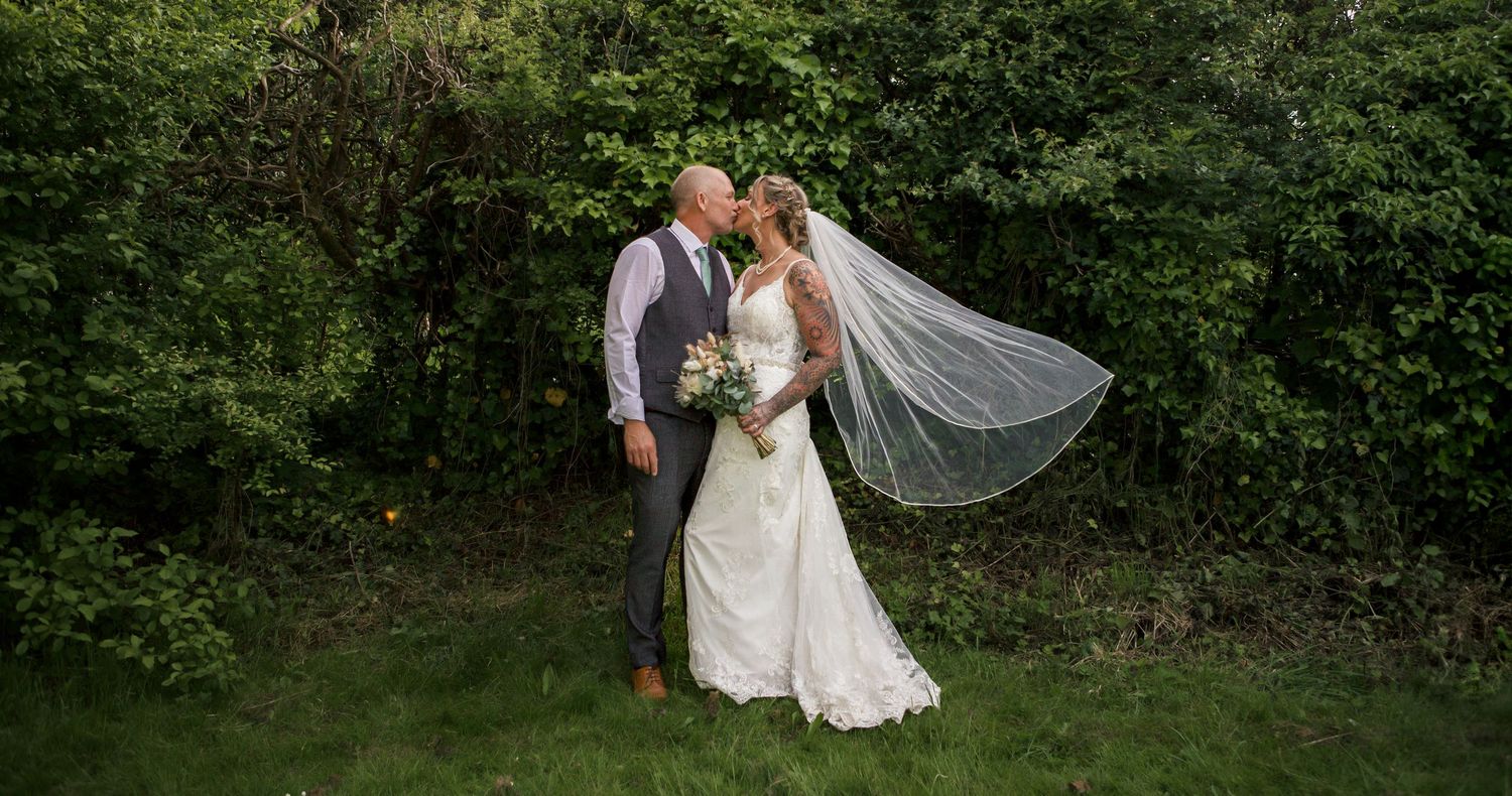 Couple poses for romantic outdoor wedding photos in a lush garden setting.