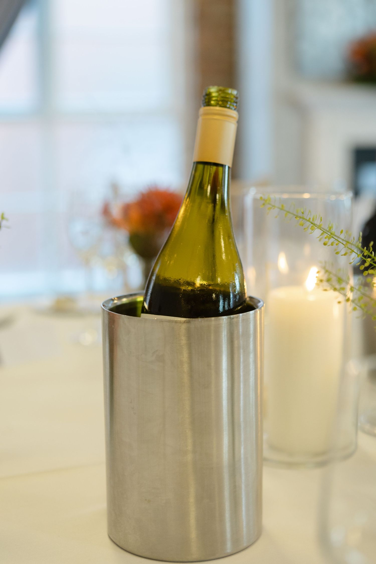 Wine bottles in silver coolers on an elegant white tablecloth.